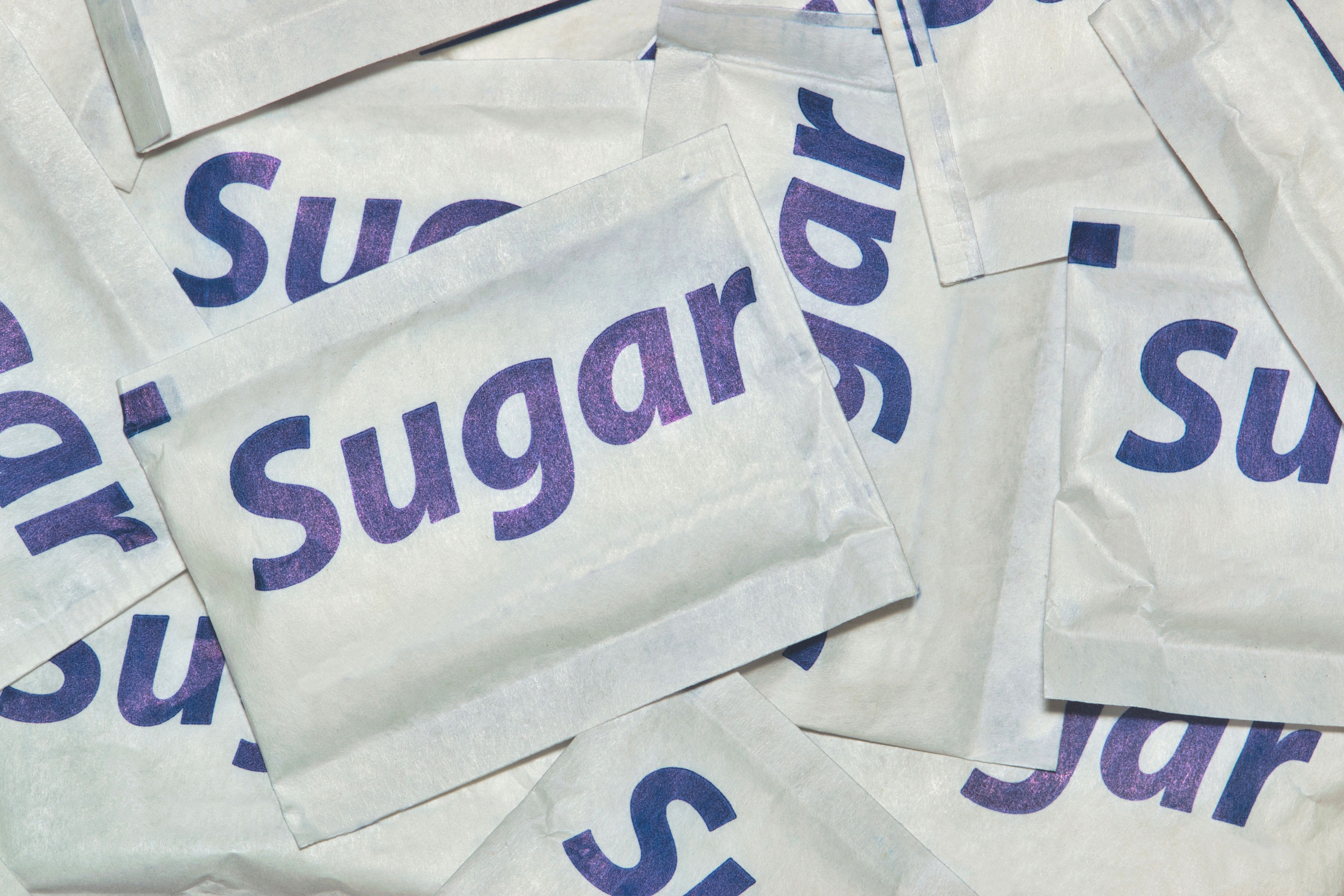 Packets of generic brand natural white sugar scattered loosely.