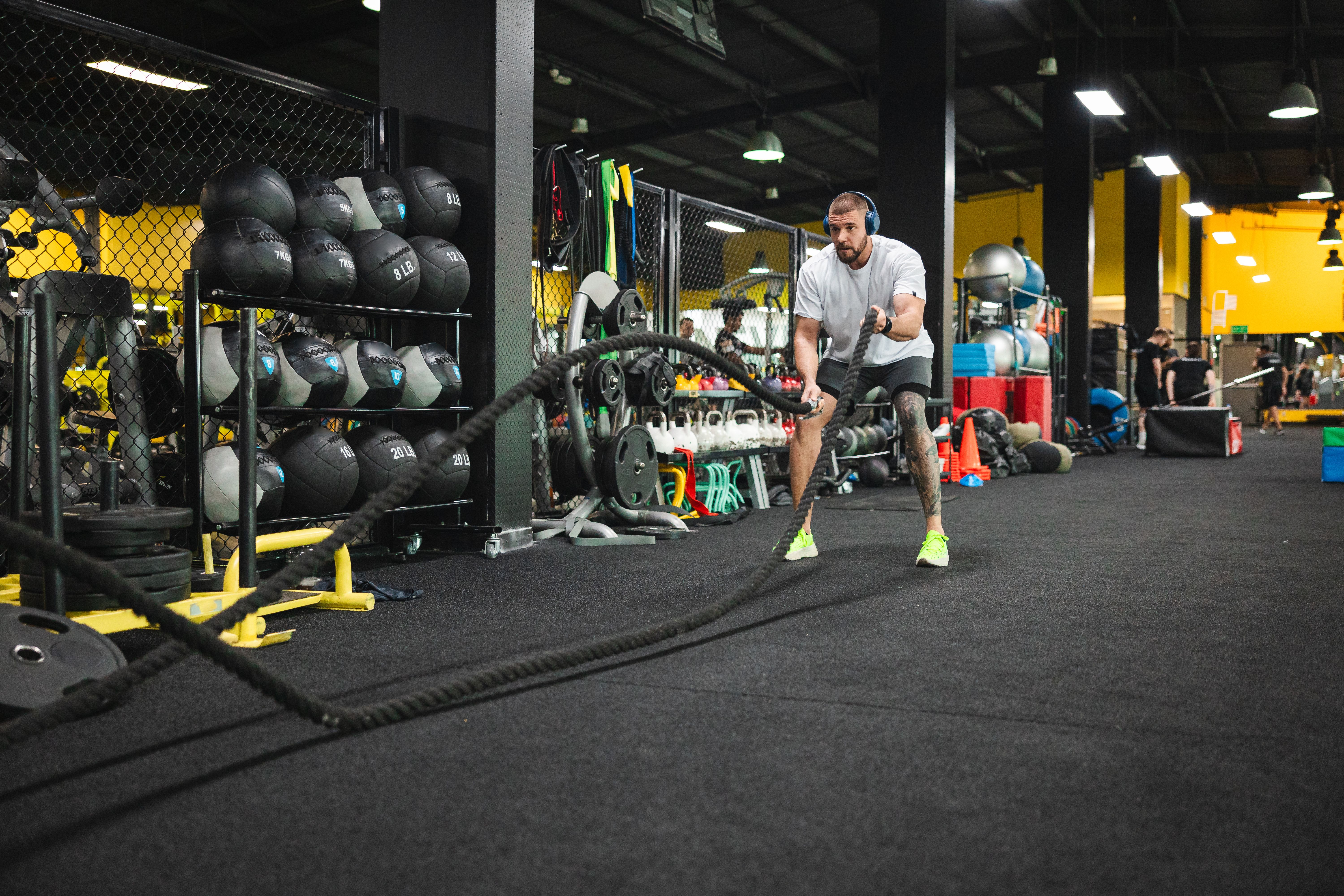 Young man working out at the gym by using ropes