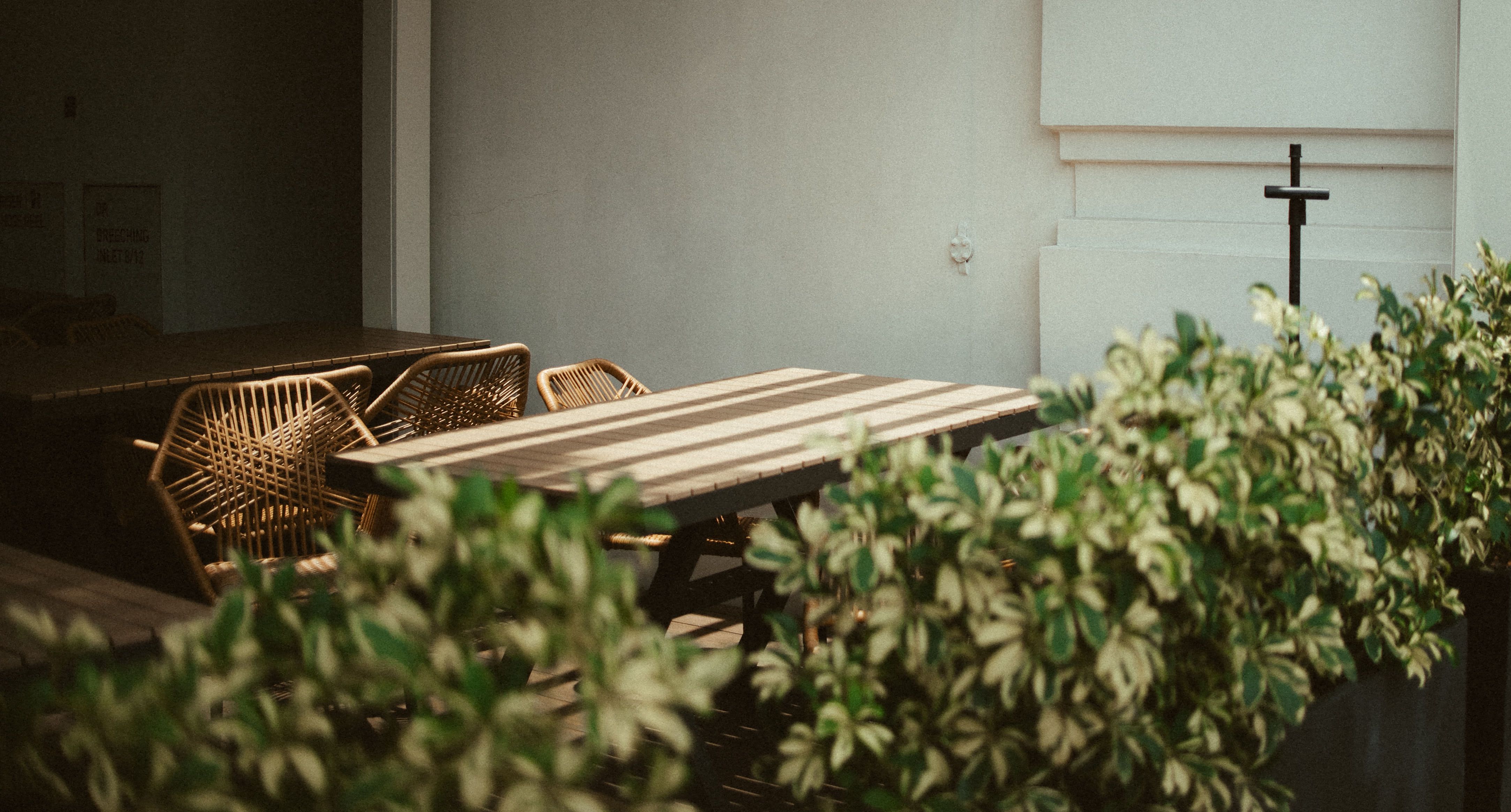 Sunlit Wooden Table with Rattan Chairs for Outdoor Dining Aesthetic, Singapore, Southeast Asian Vibes, Urban Oasis, Al Fresco Dining, Wooden Furniture, Plant Decor, Outdoor Café Scene