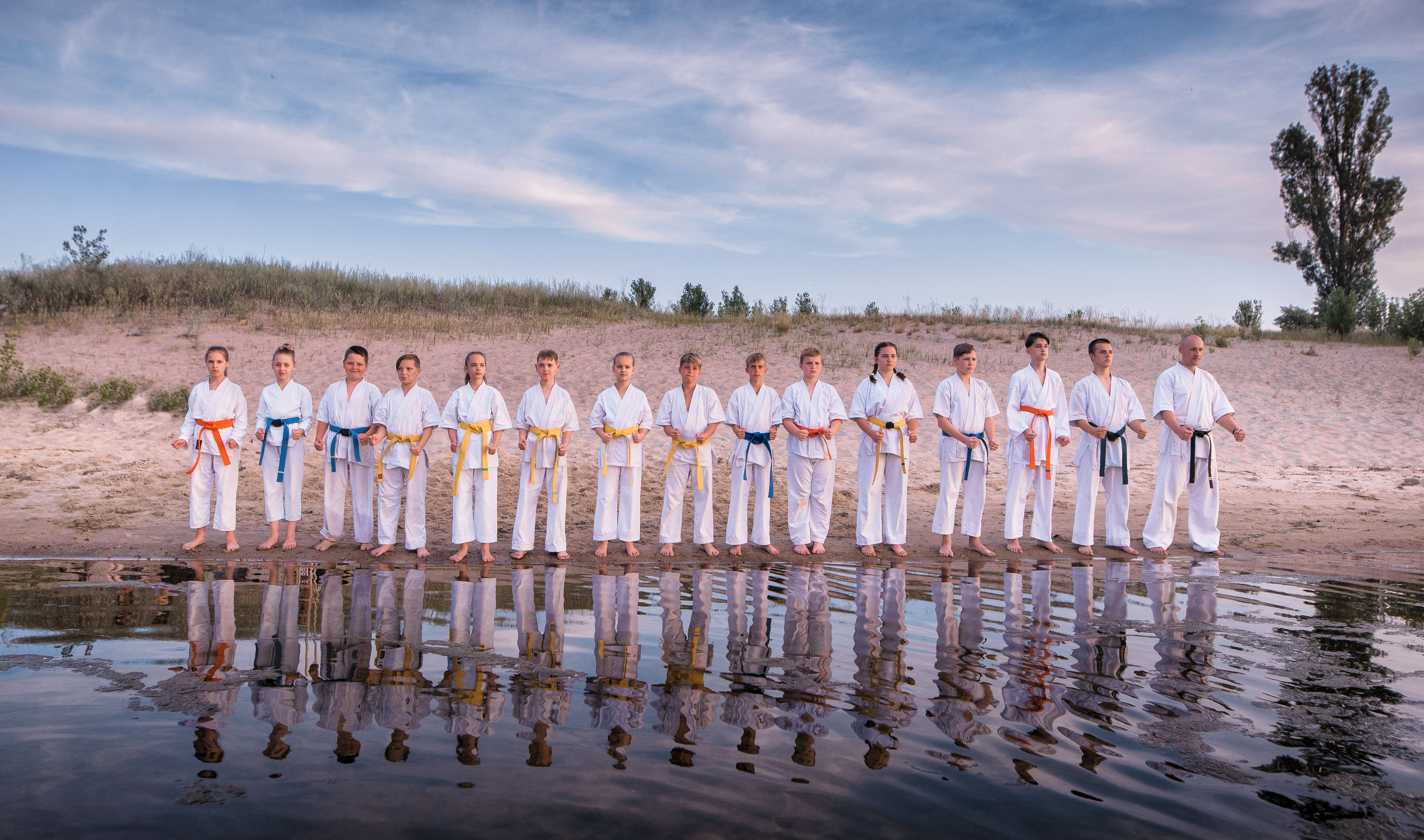 Karate kids team standing on sunset beach
