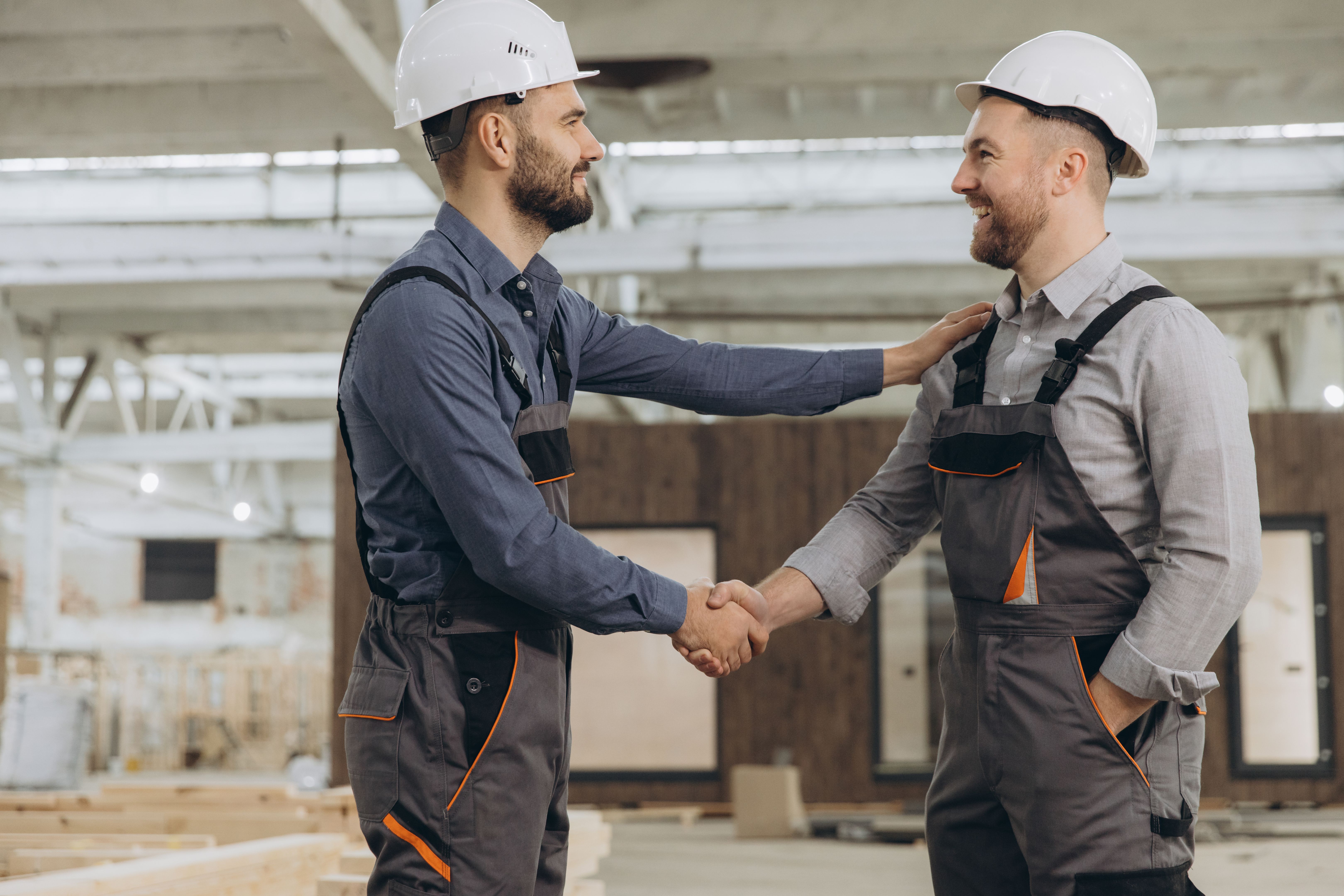 Construction workers shaking hands in modular building factory