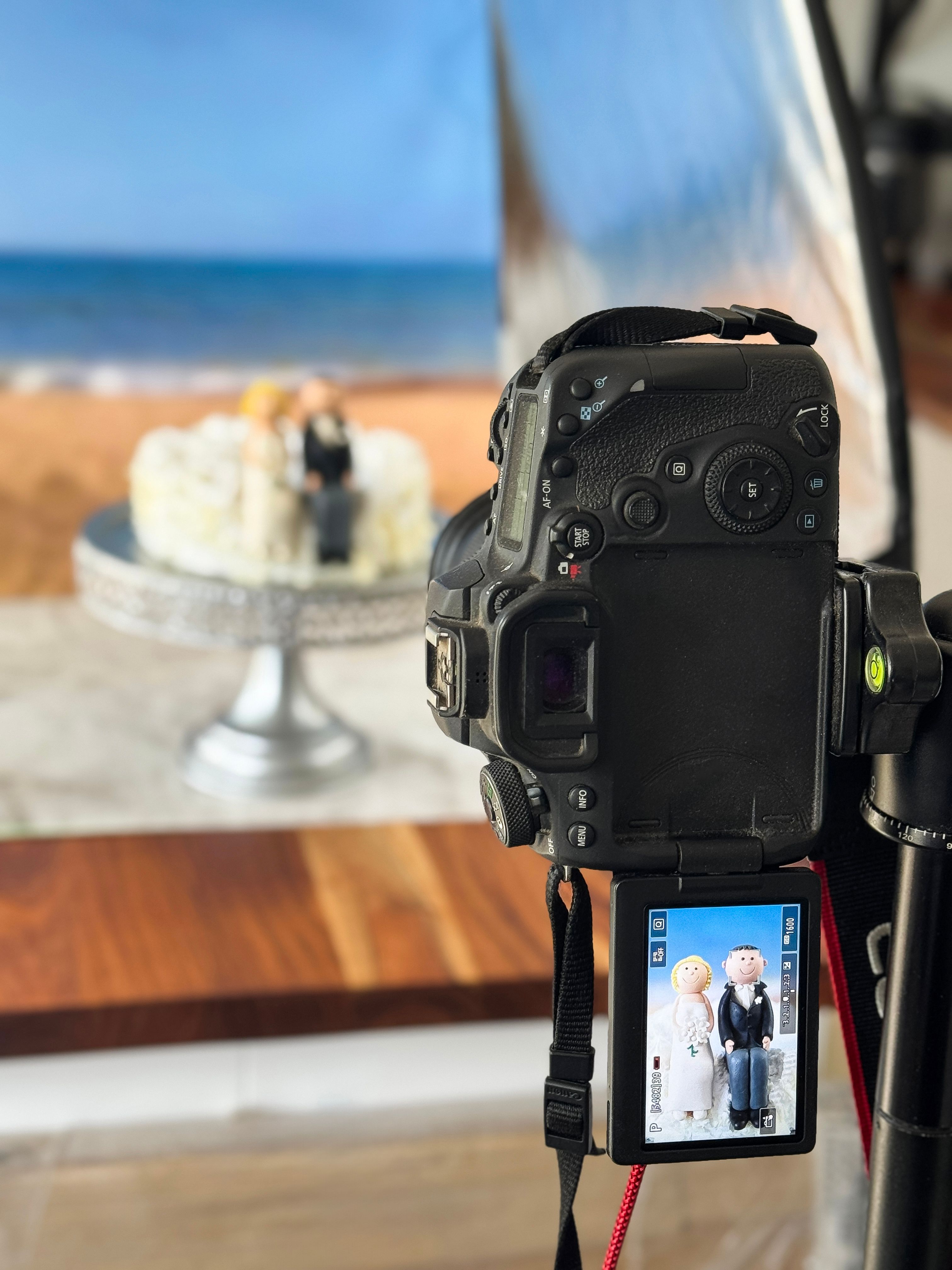 Image des coulisses de la séance photo du studio de photographie culinaire mise en place, prise de photos à l’intérieur de la couche de gâteau de mariage sur le présentoir à gâteaux, figurines de la mariée et du marié, glaçage fondant décorati