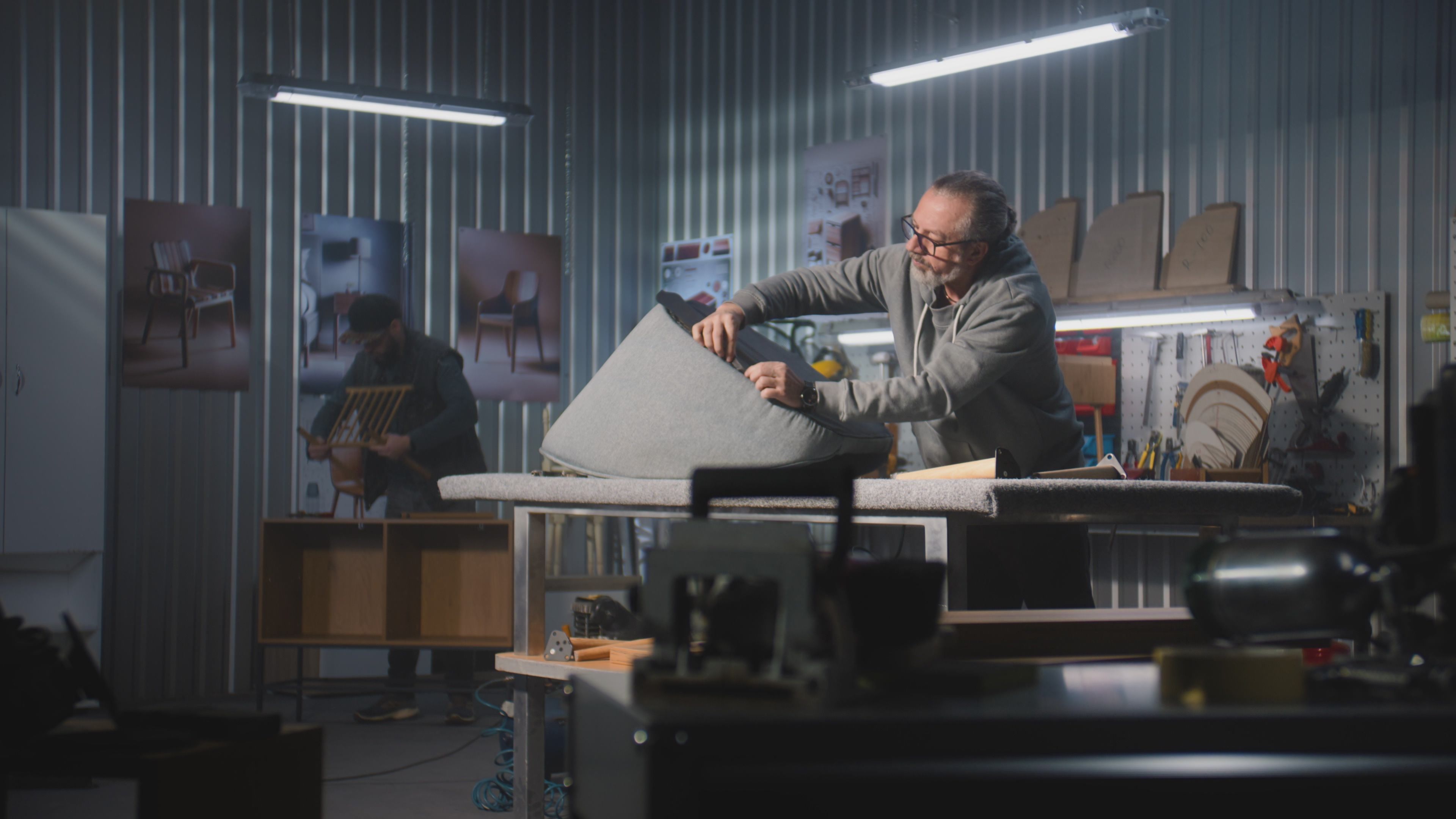Mature carpenter makes upholstery of chair using staple gun
