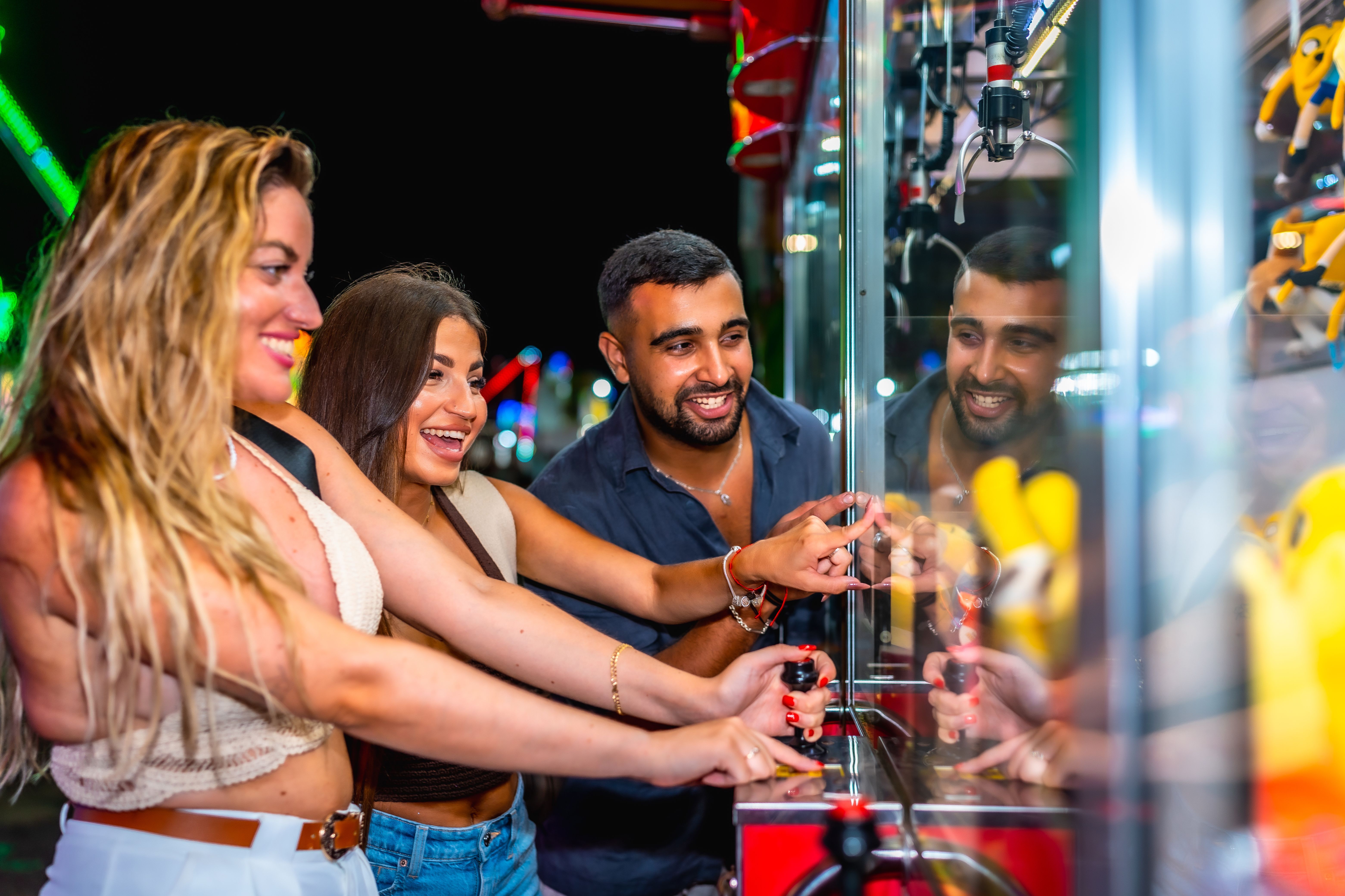 Friends playing claw crane game at amusement park