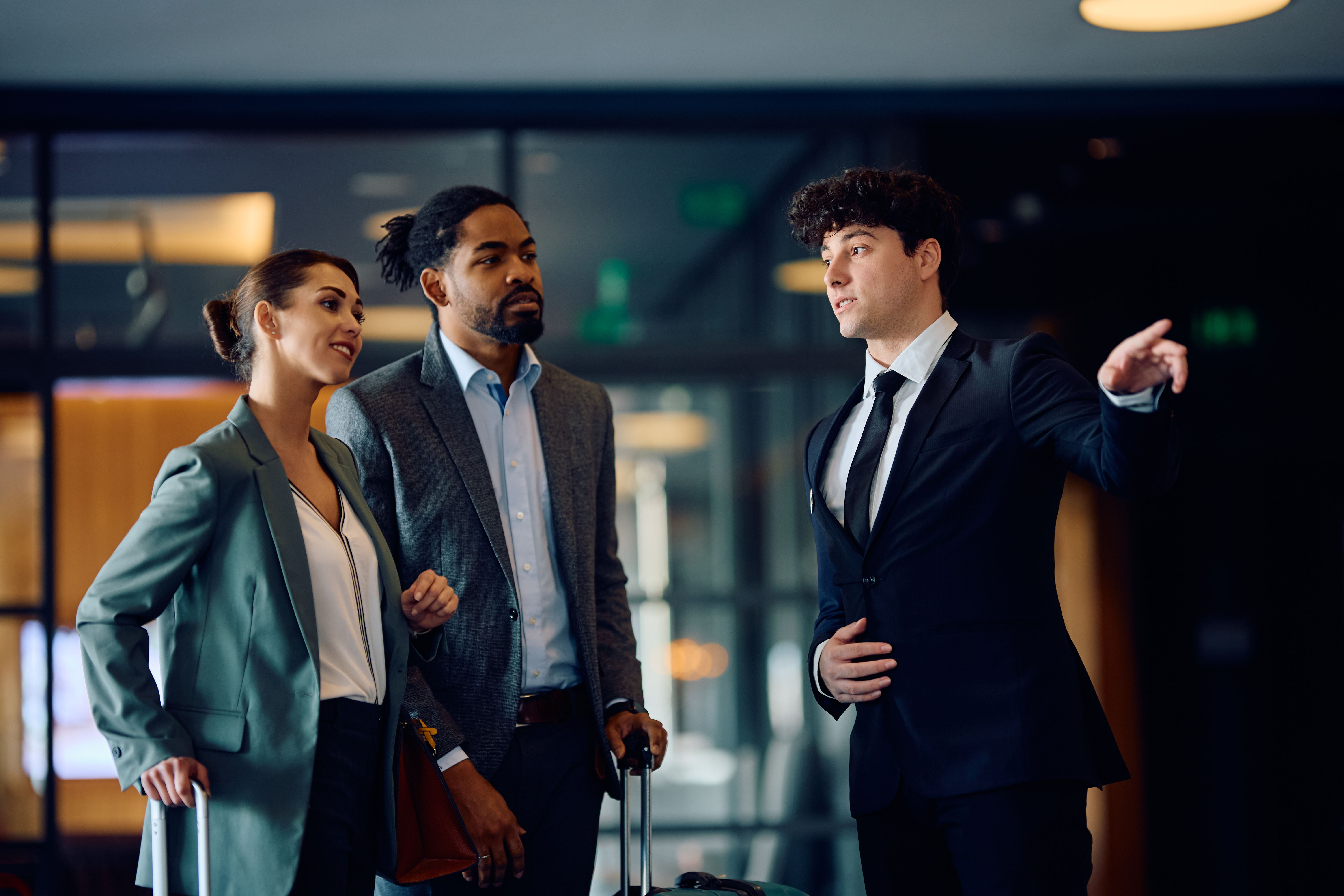 Hotel manager talking to a business couple in a hallway.