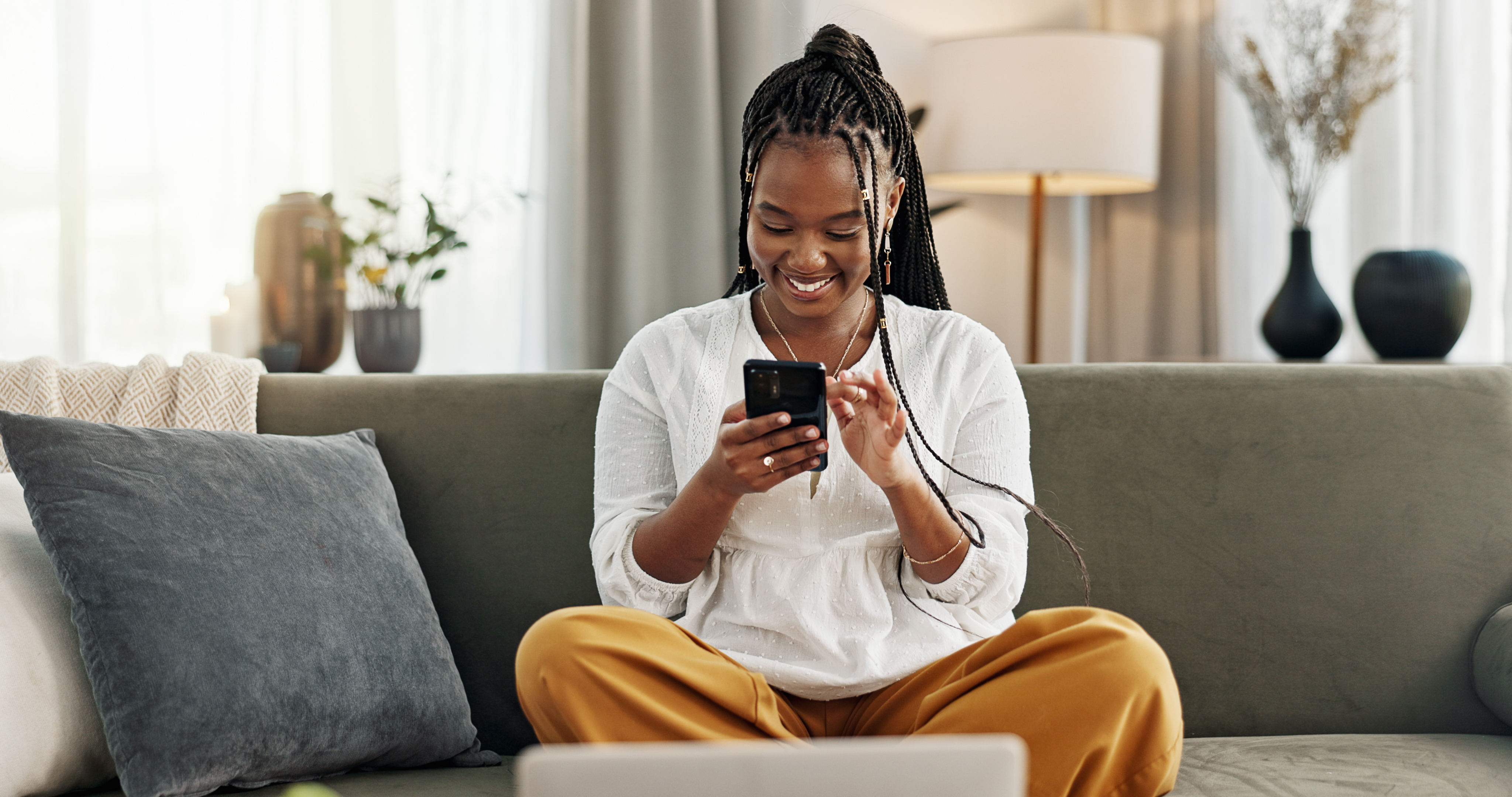 Home, funny and black woman on a sofa, cellphone and connection with social media, comedy post and laugh. African person, apartment or girl on couch, smartphone or mobile user with humor or typing