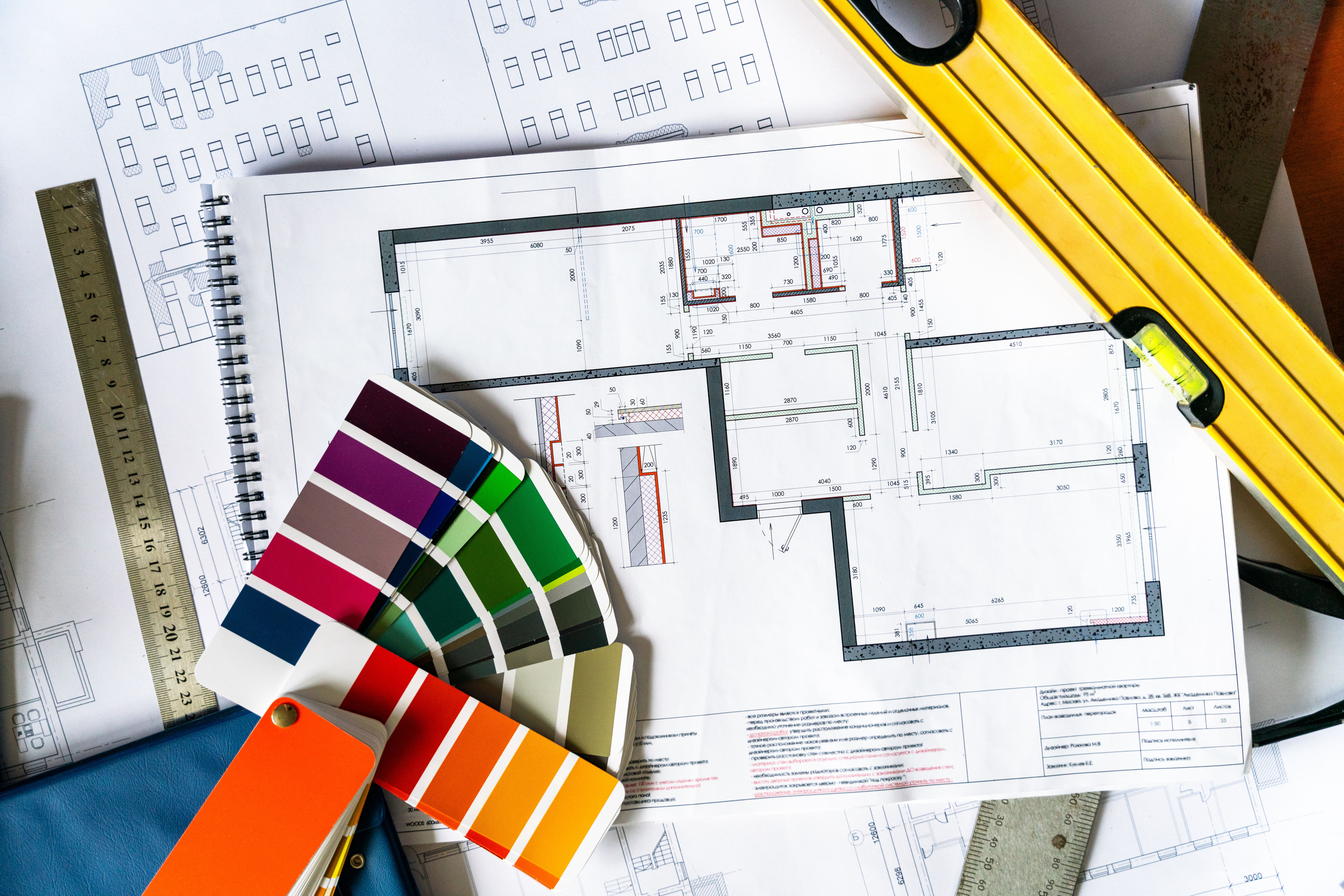 An architectural blueprints, color swatch palette and construction work tools on the desk, directly above view
