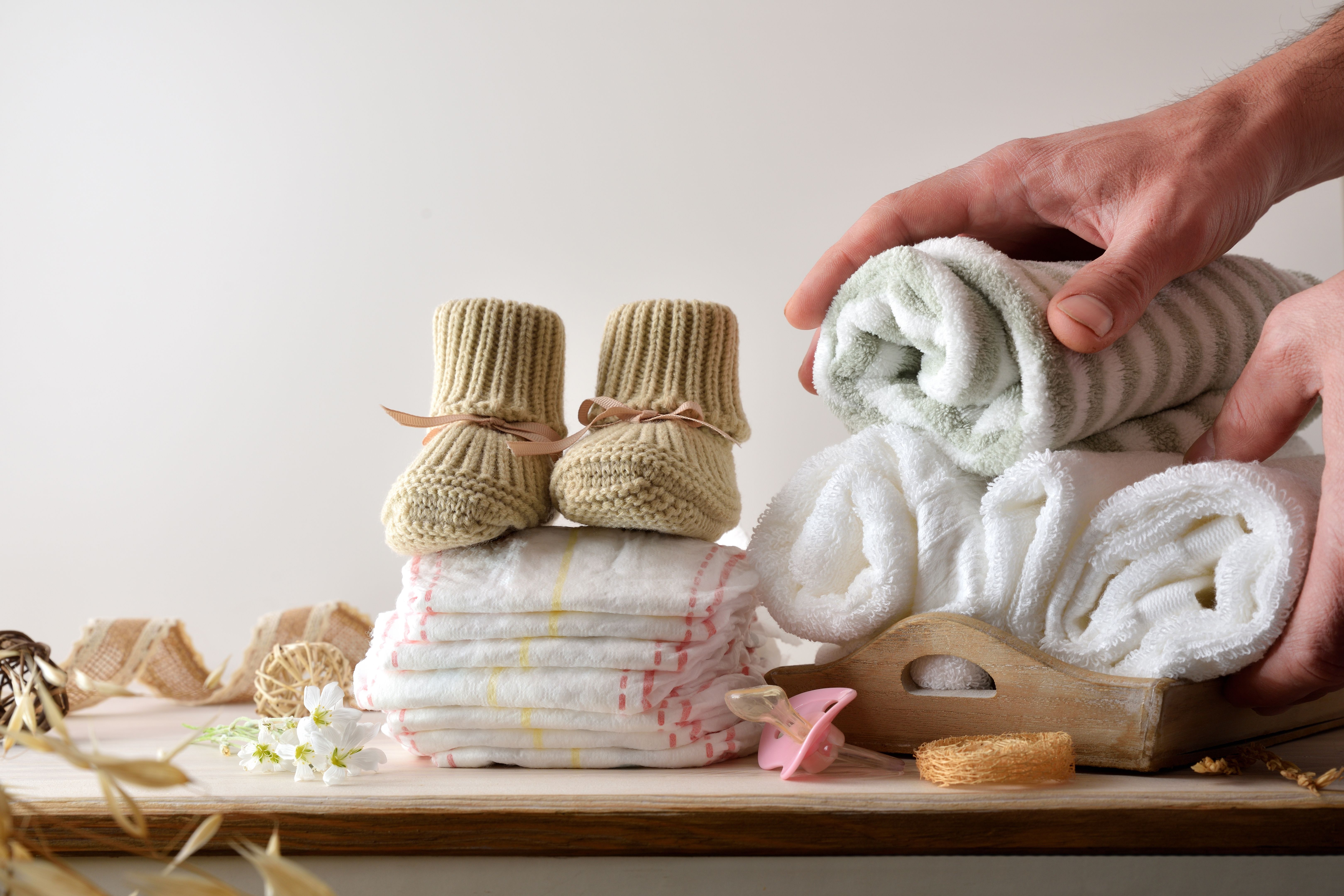 Hands preparing cloths and diapers for baby hygiene on furniture