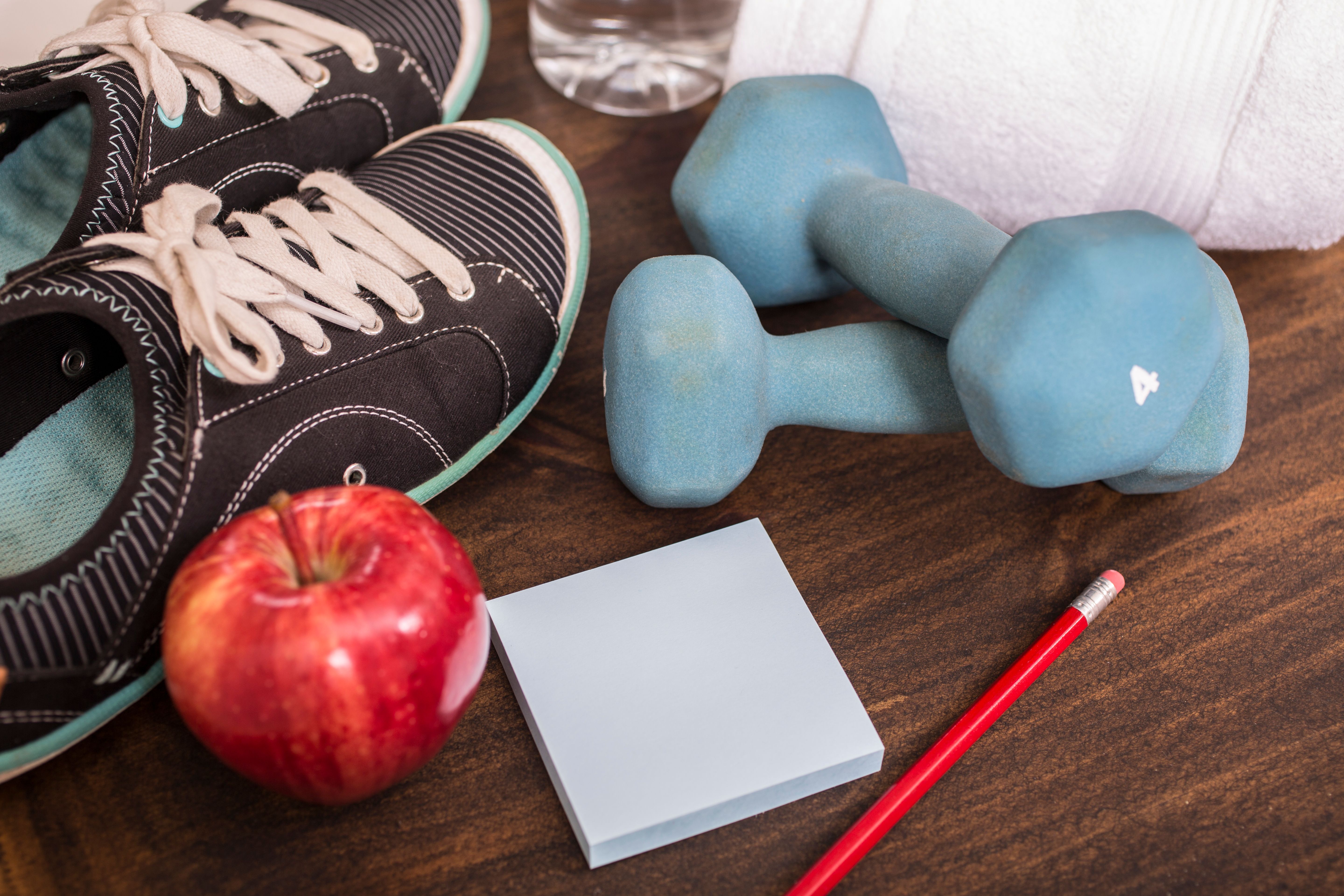 Fitness, exercise themed scene with weights, sneakers, apple.