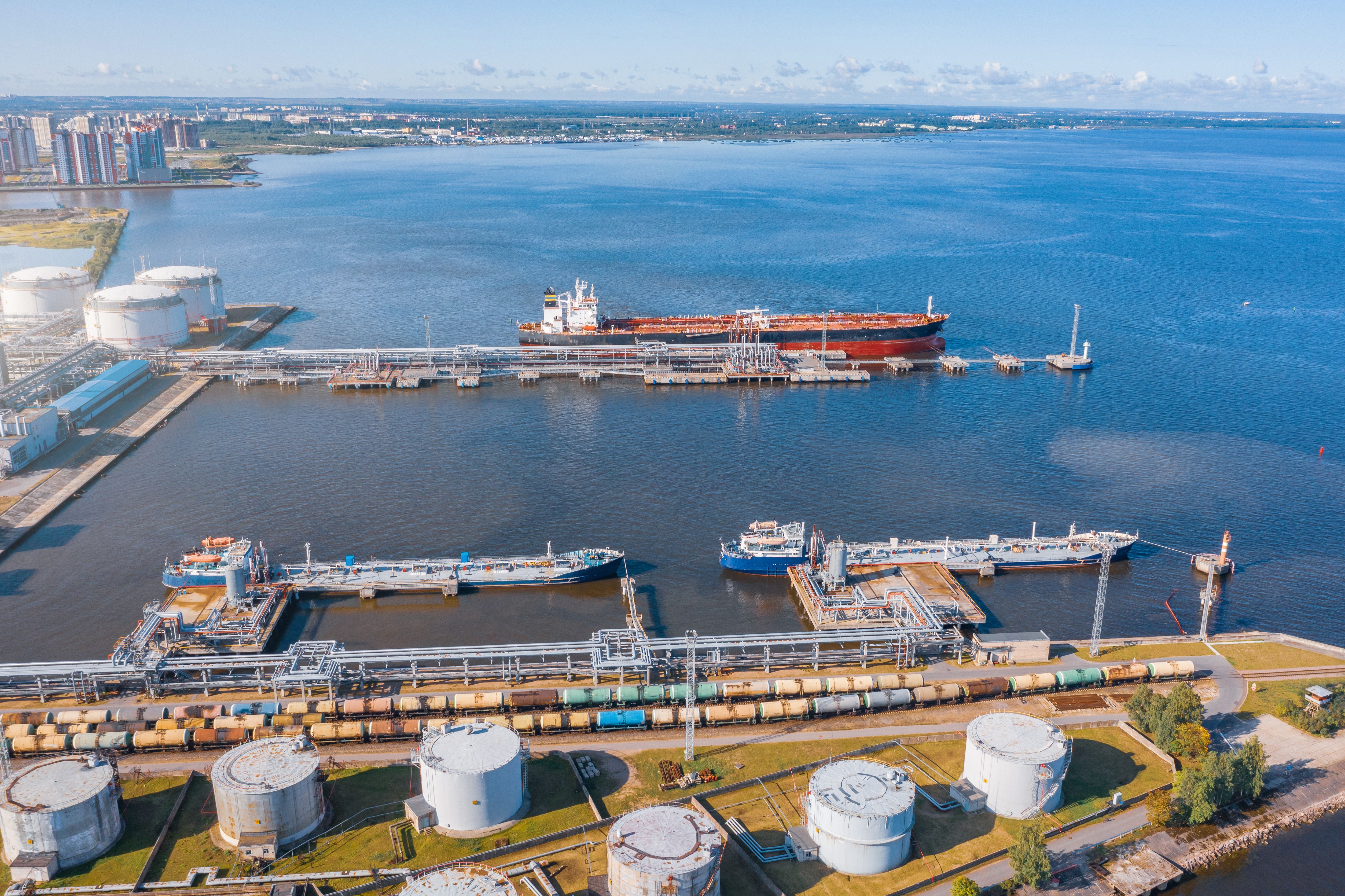 Aerial view large port oil loading terminal with large storage tanks. Railway infrastructure for the delivery of bulk cargo by sea, using pump station in ship tanker for transportation and delivery.