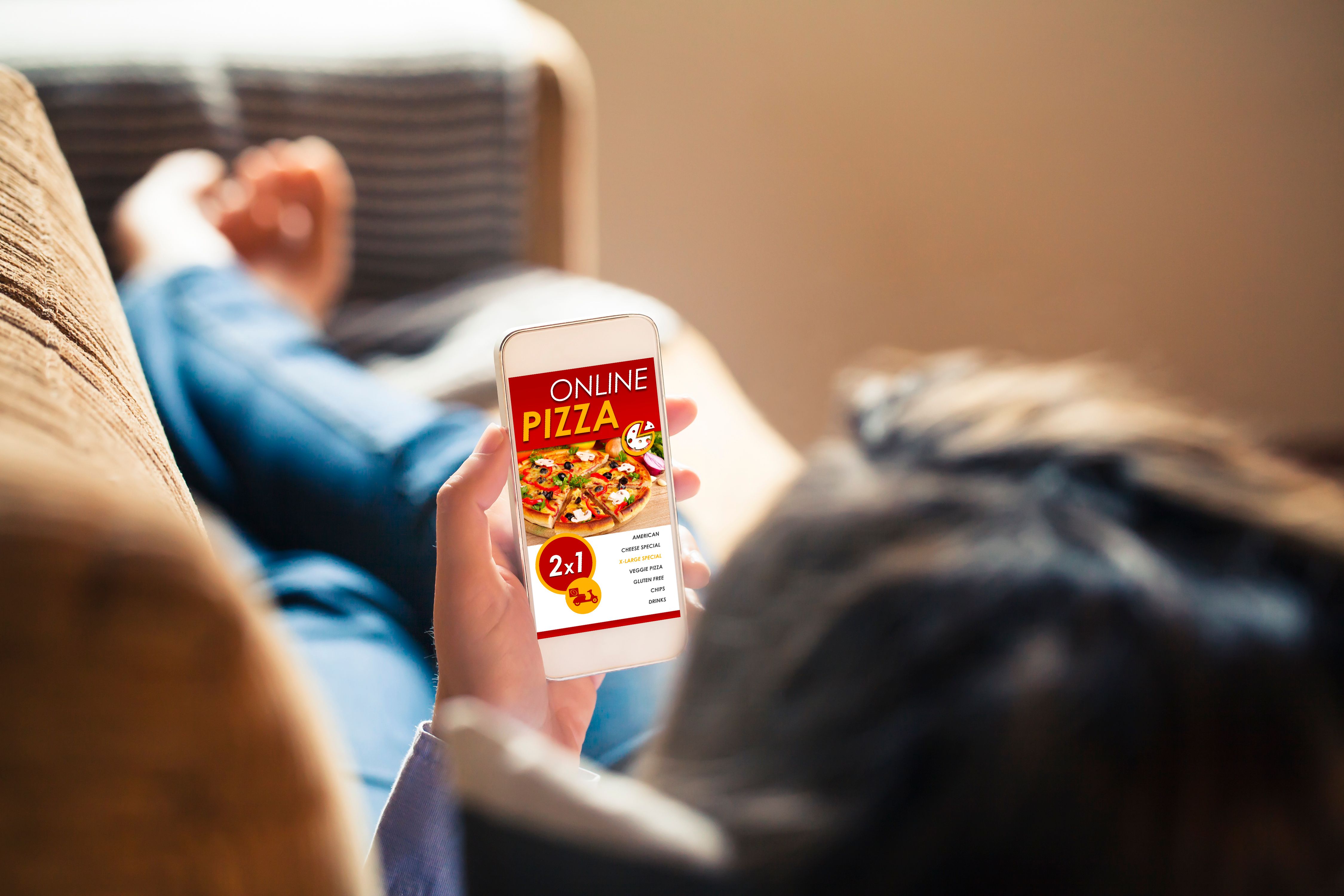Woman holding a mobile phone with pizza shop website in the screen. Woman holding a mobile phone with pizza shop website in the screen.