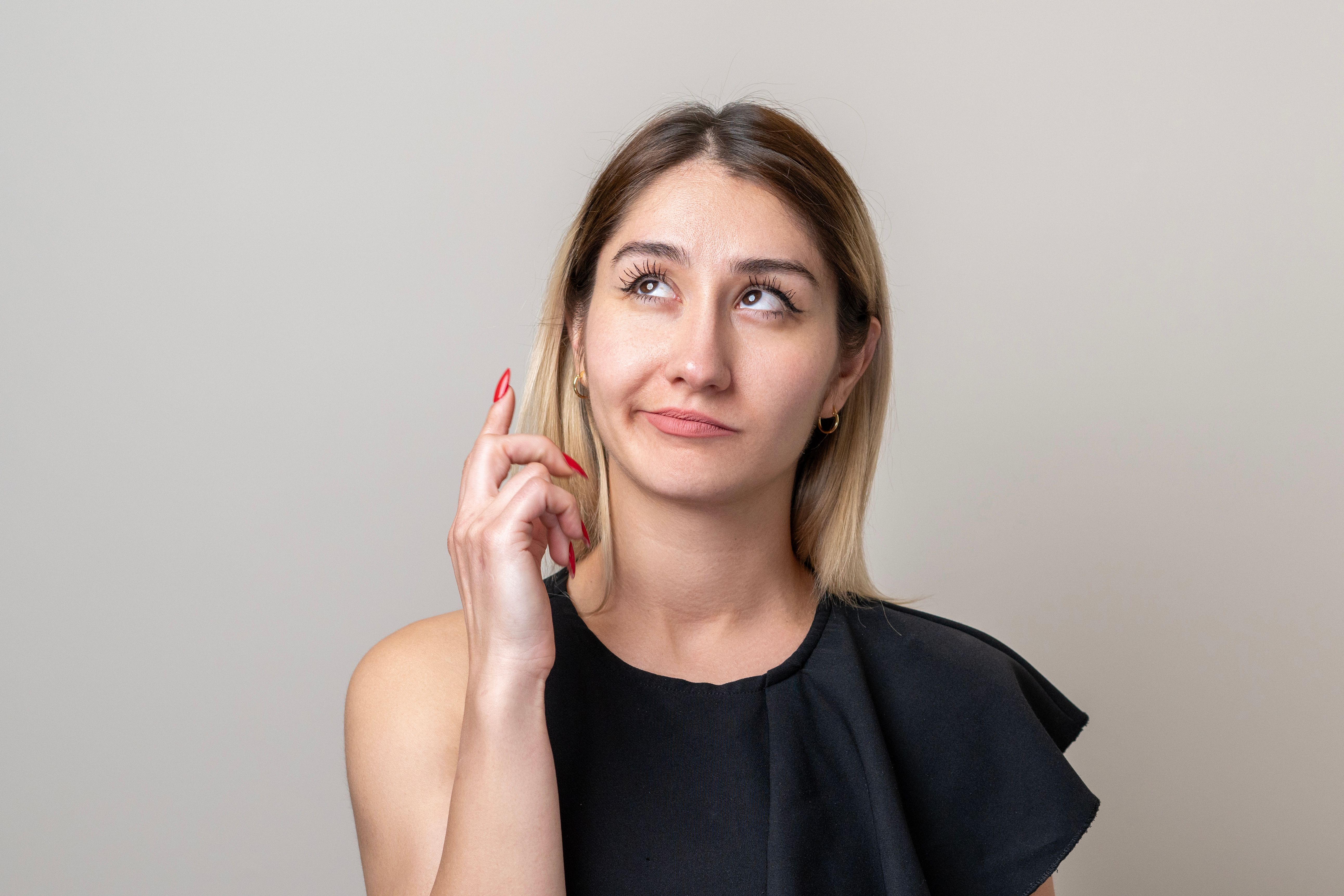 Portrait of mid adult female thinking over bright gray background Portrait of mid adult female thinking over bright gray background