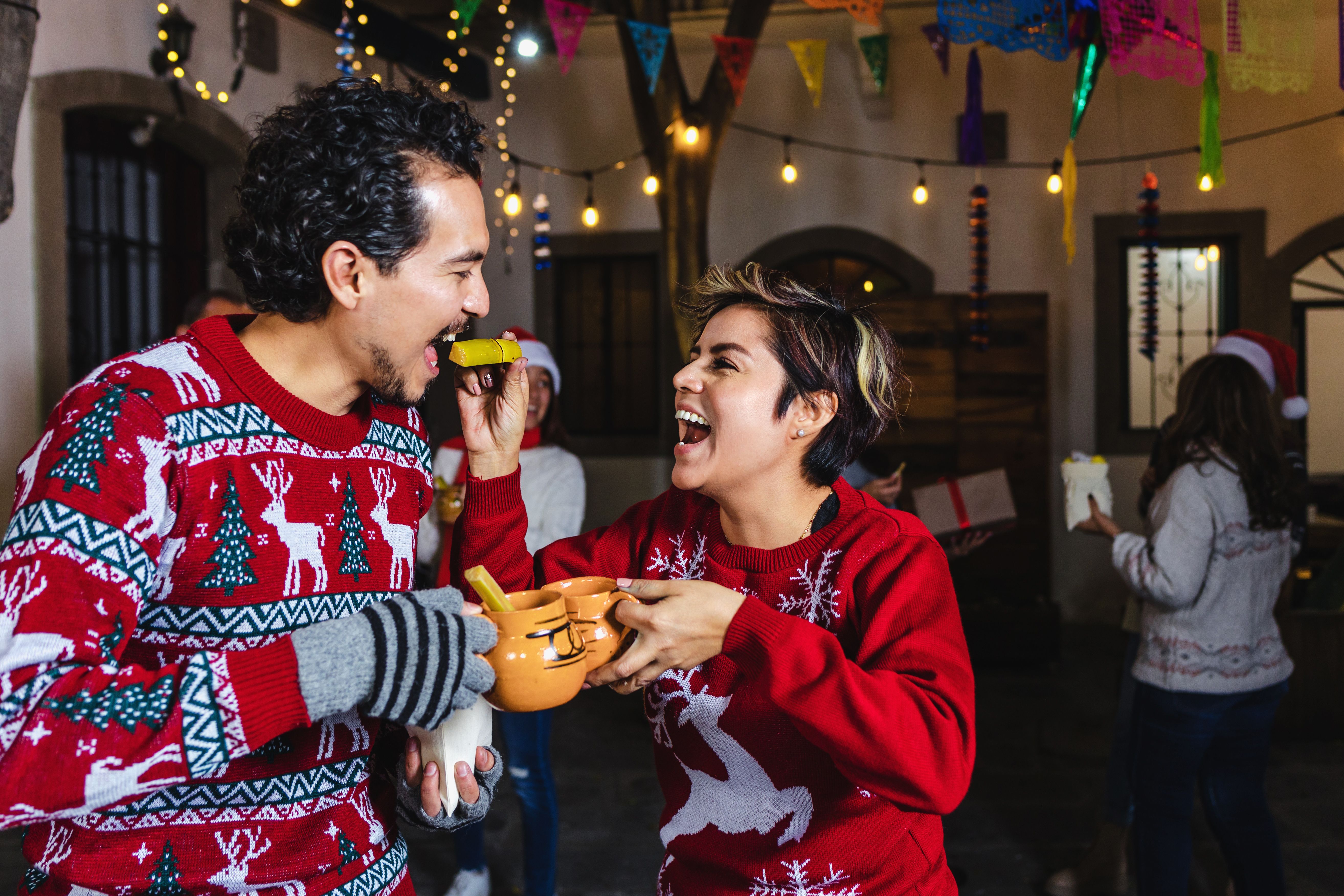 Mexican young couple or friends having fun in posada celebration for Christmas eve in Mexico Latin America, hispanic holidays