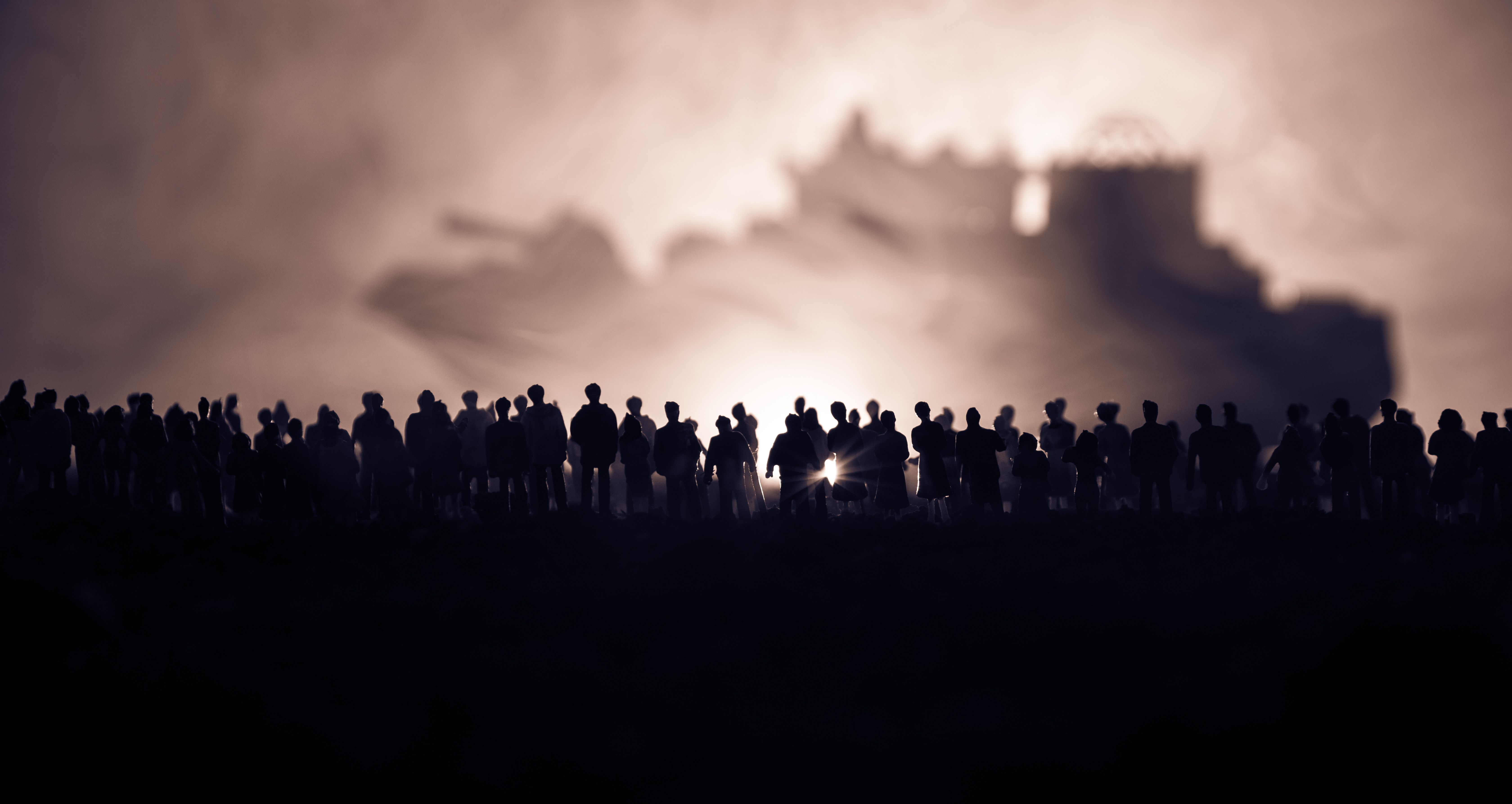 Silhouettes of a crowd standing at blurred military war ship on foggy background. Selective focus. Passengers try to escape.