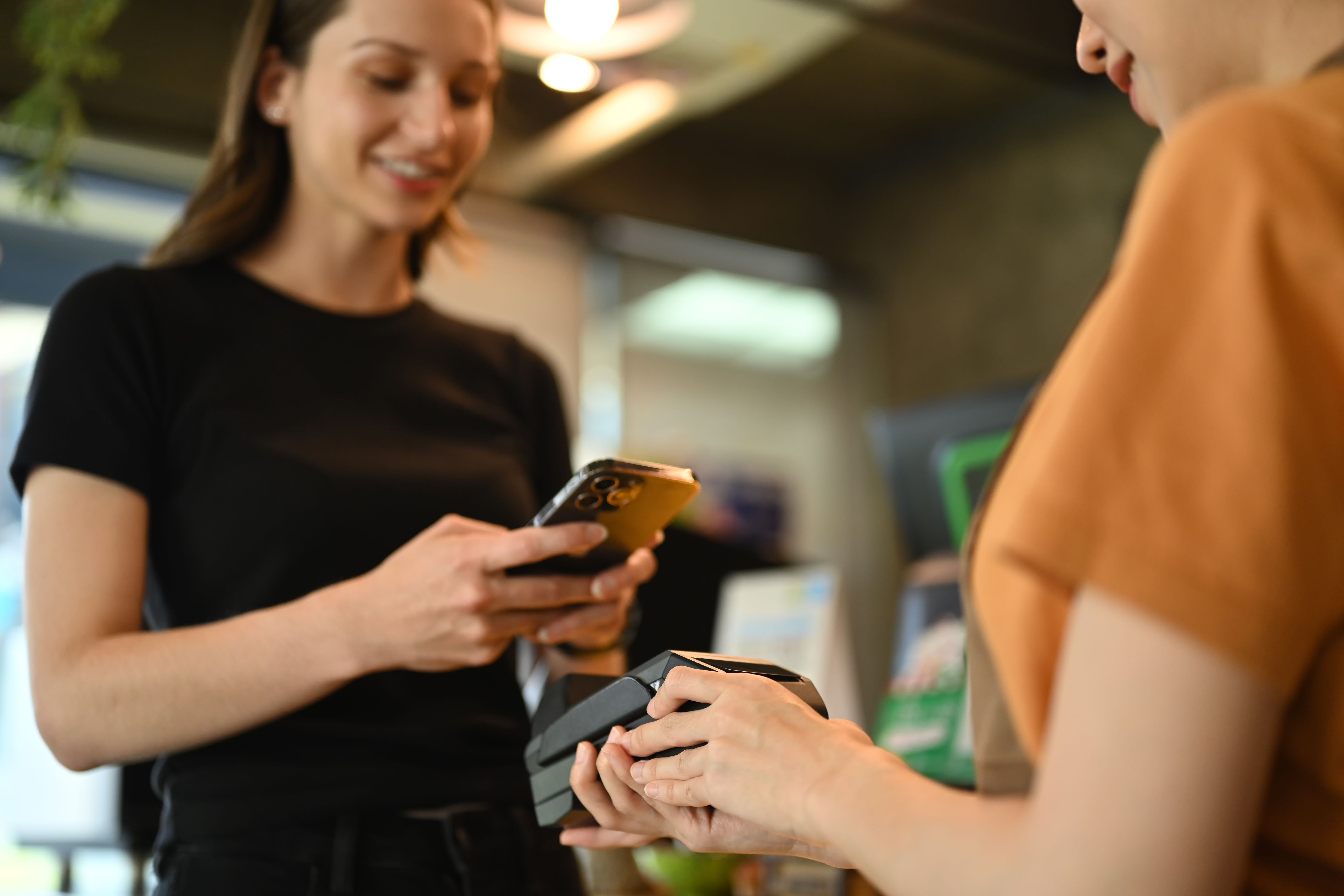 Closeup shot of caucasian female customer holding smart phone scanning qr code for cashless payment at cafeteria.