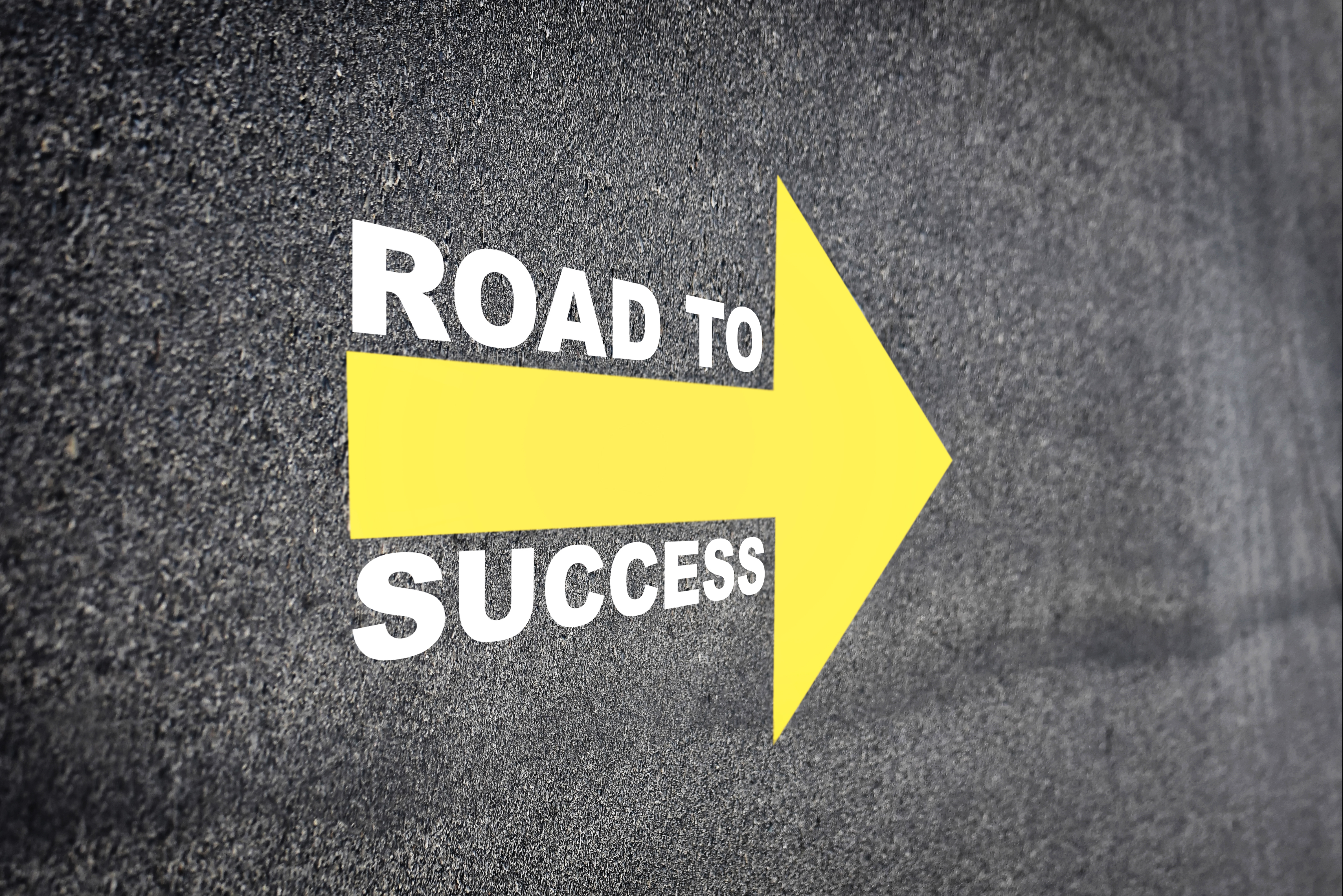 Road to success with yellow arrow marking on road surface