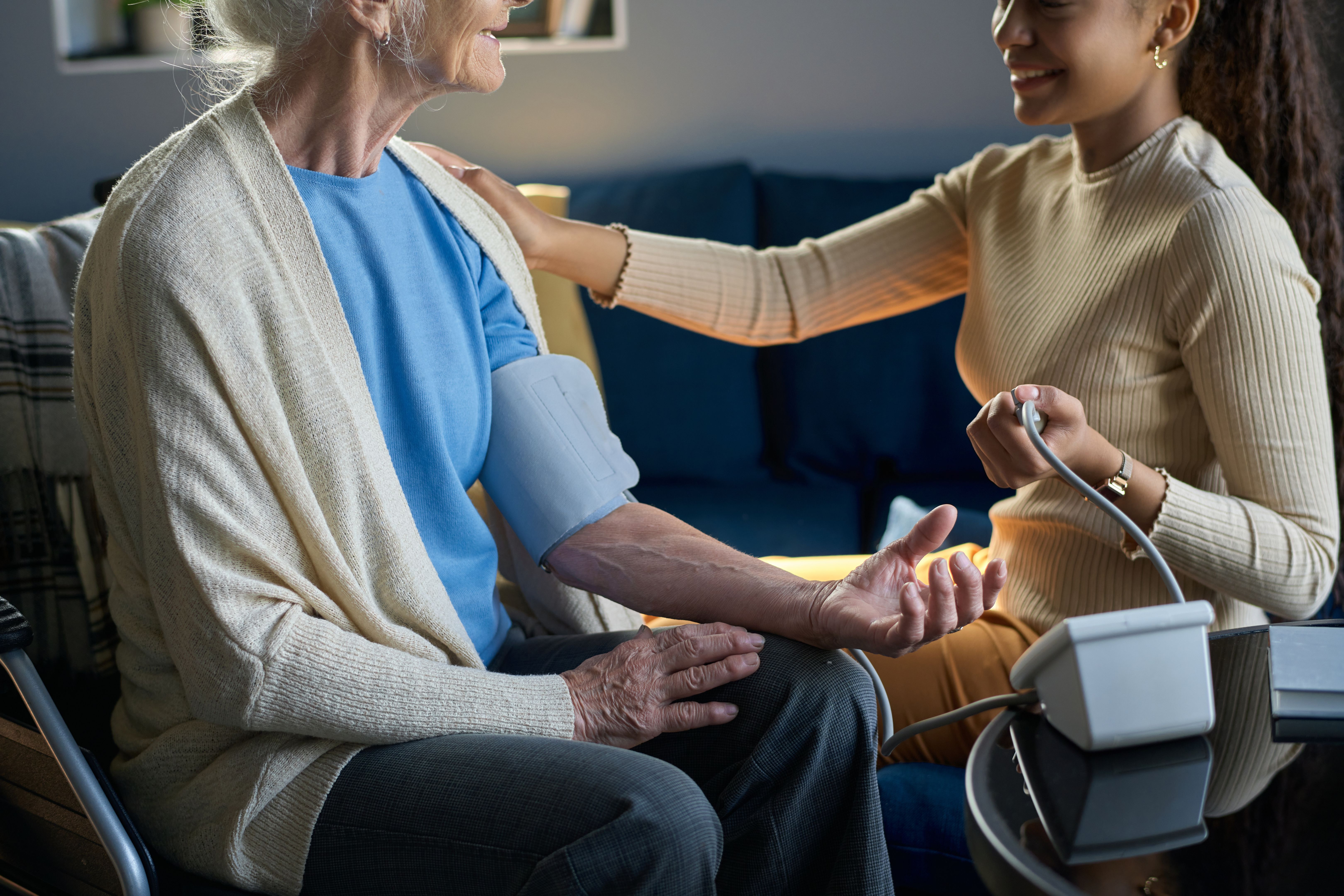 Cropped shot of smiling teenage girl measuring blood pressure of her grandmother