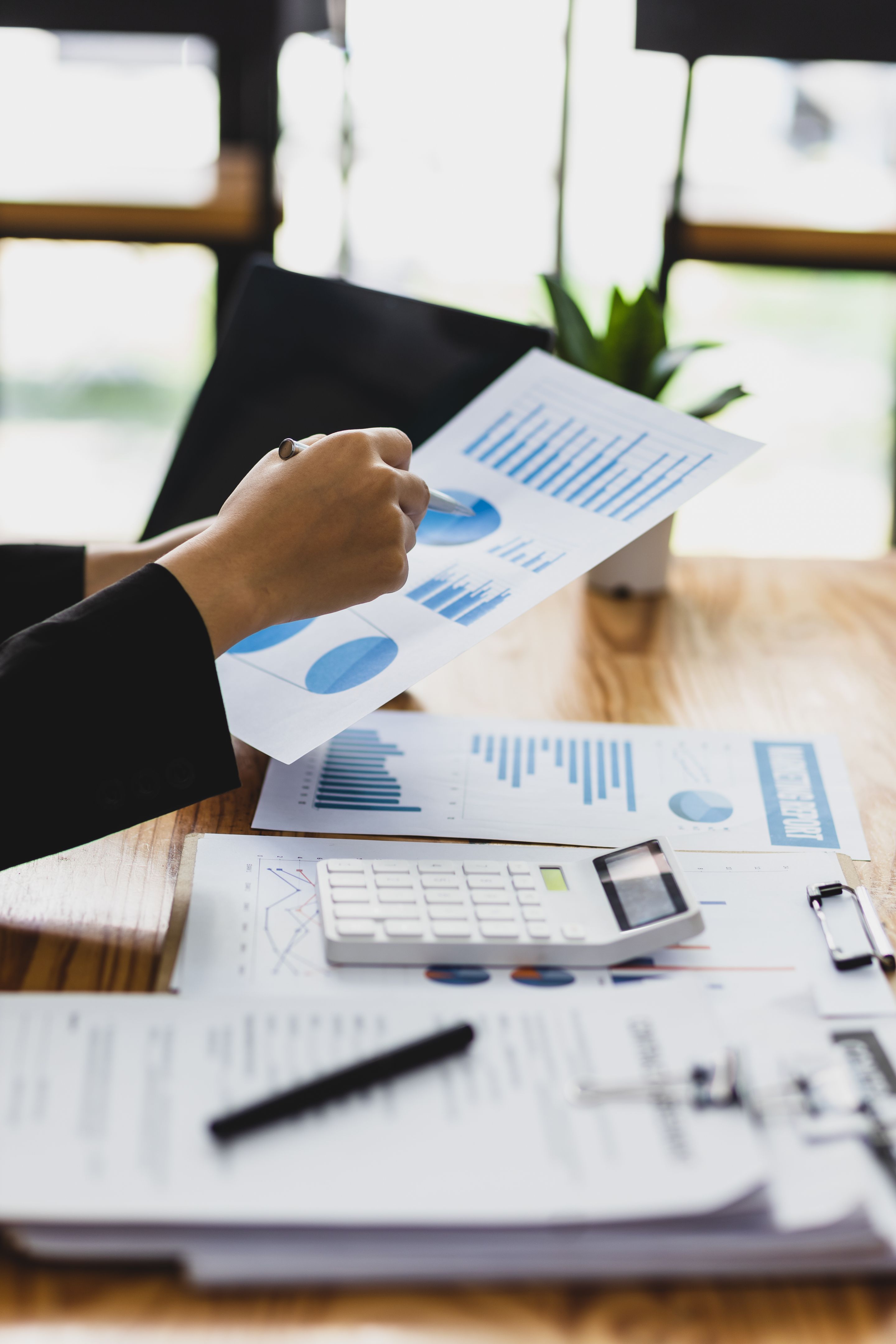 Businesswoman working on paperwork, Analysis of financial report documents and investment charts on laptop.