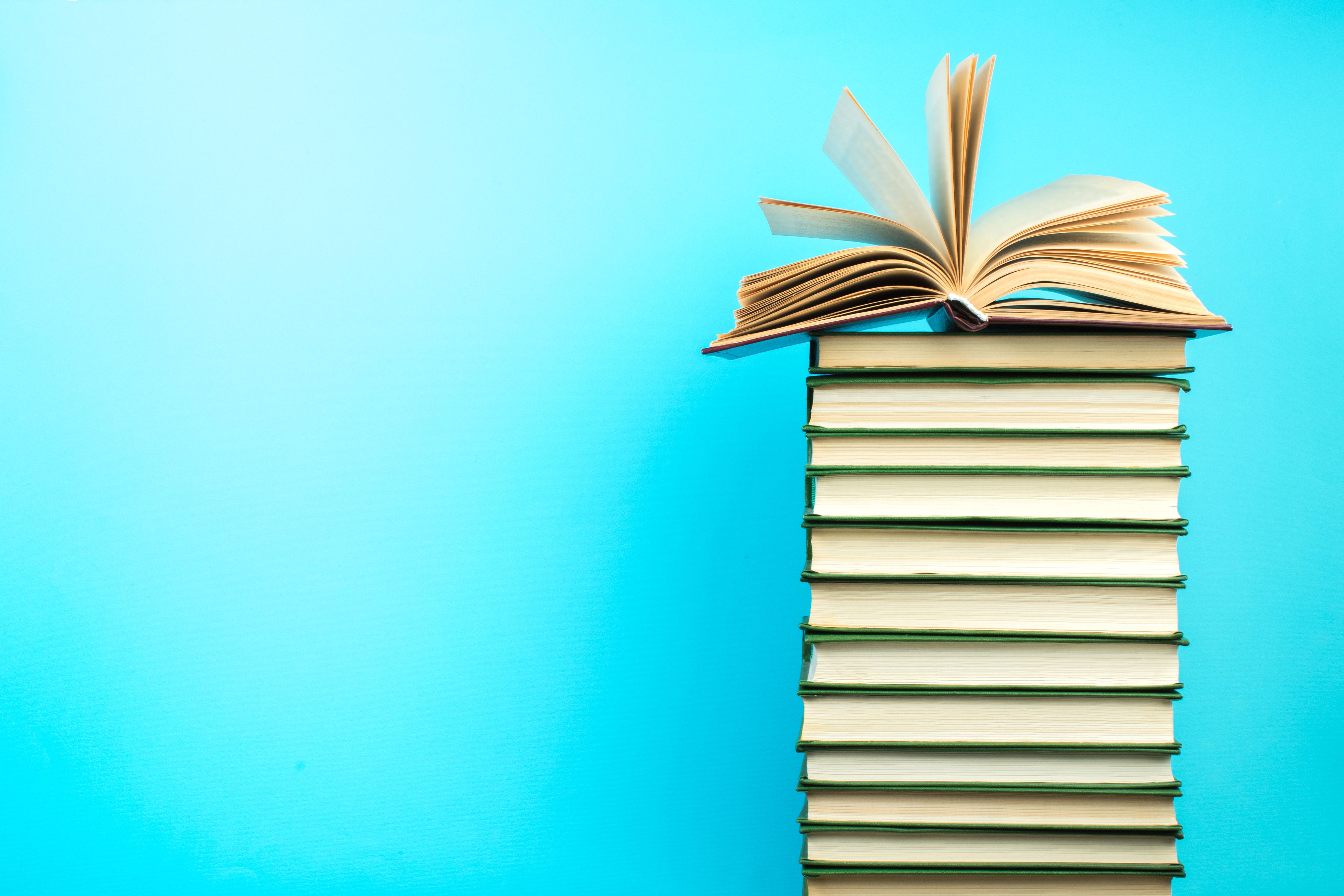 Open book, hardback books on wooden table, on a blue background. Back to school. Copy space for text. Education background. Open book, hardback books on wooden table, on a blue background. Back to school. Copy space for text. Education background.