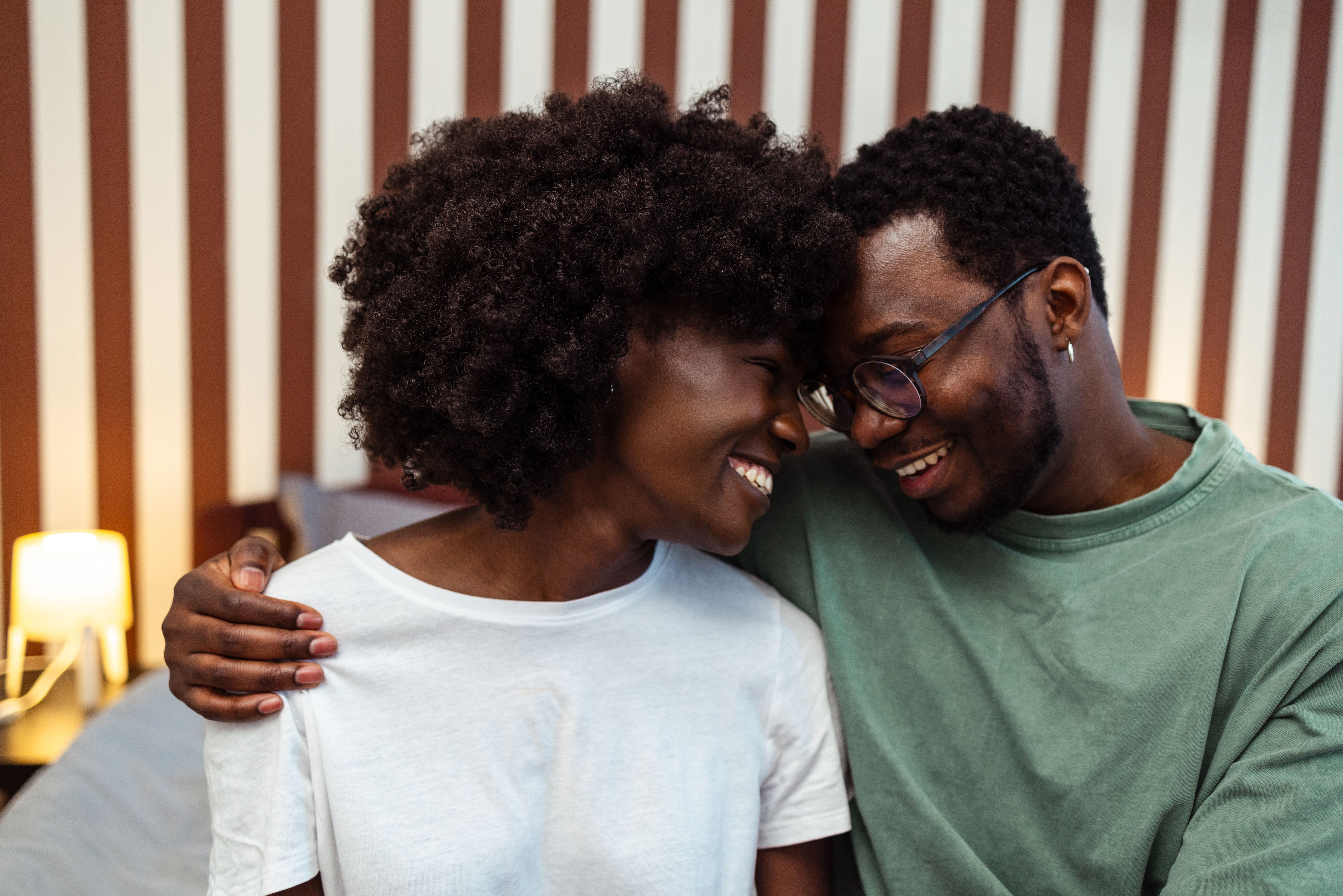 A cheerful man and woman with Afro hairstyle hugging