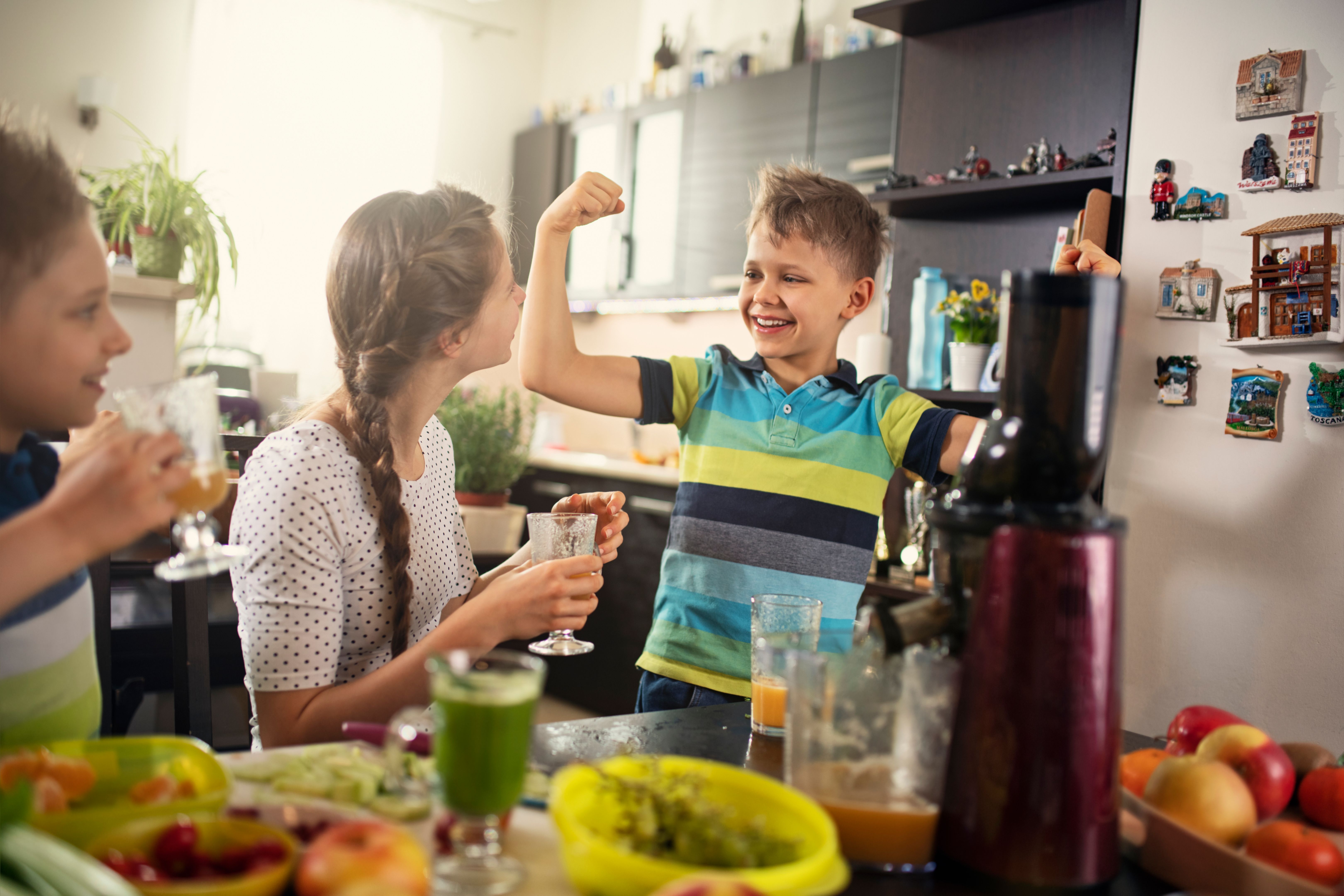 Little boy feeling strong after drinking fresh juice from fruits and vegetables