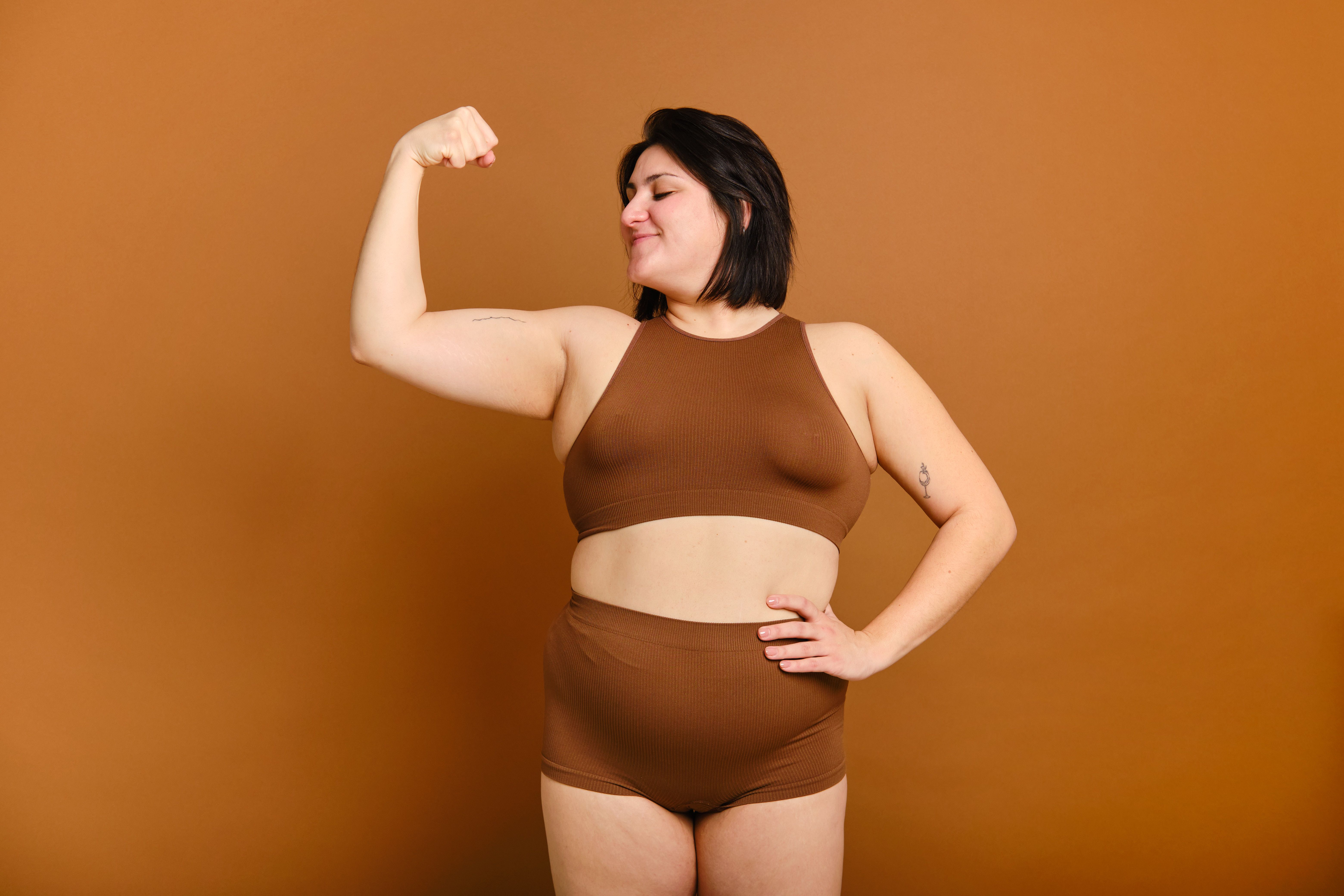 medium shot. woman showing her biceps and expressing strength and confidence