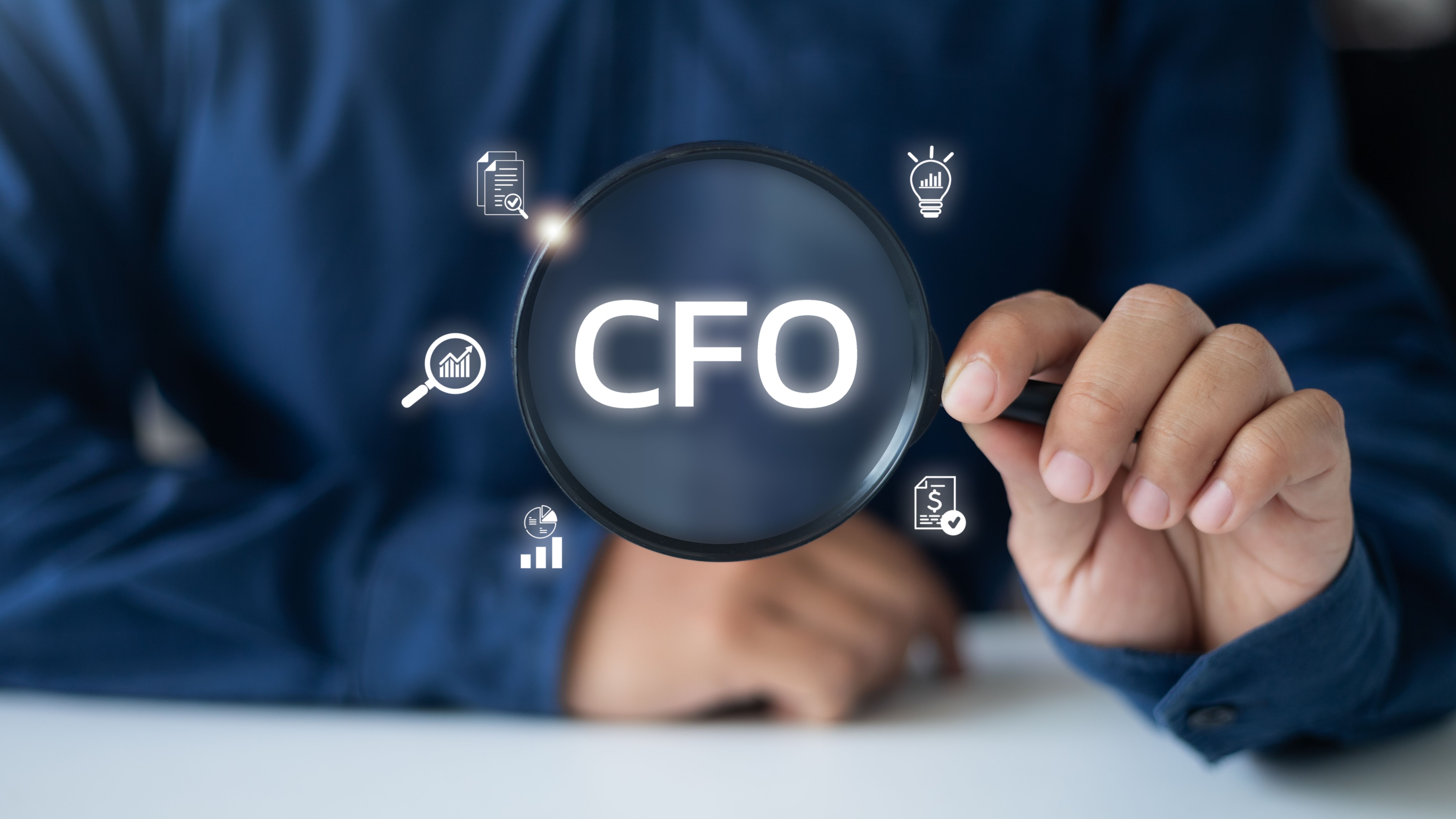 Businessman holding a magnifying glass, highlighting the CFO role with financial icons, representing executive leadership in corporate finance, strategy, and accounting.