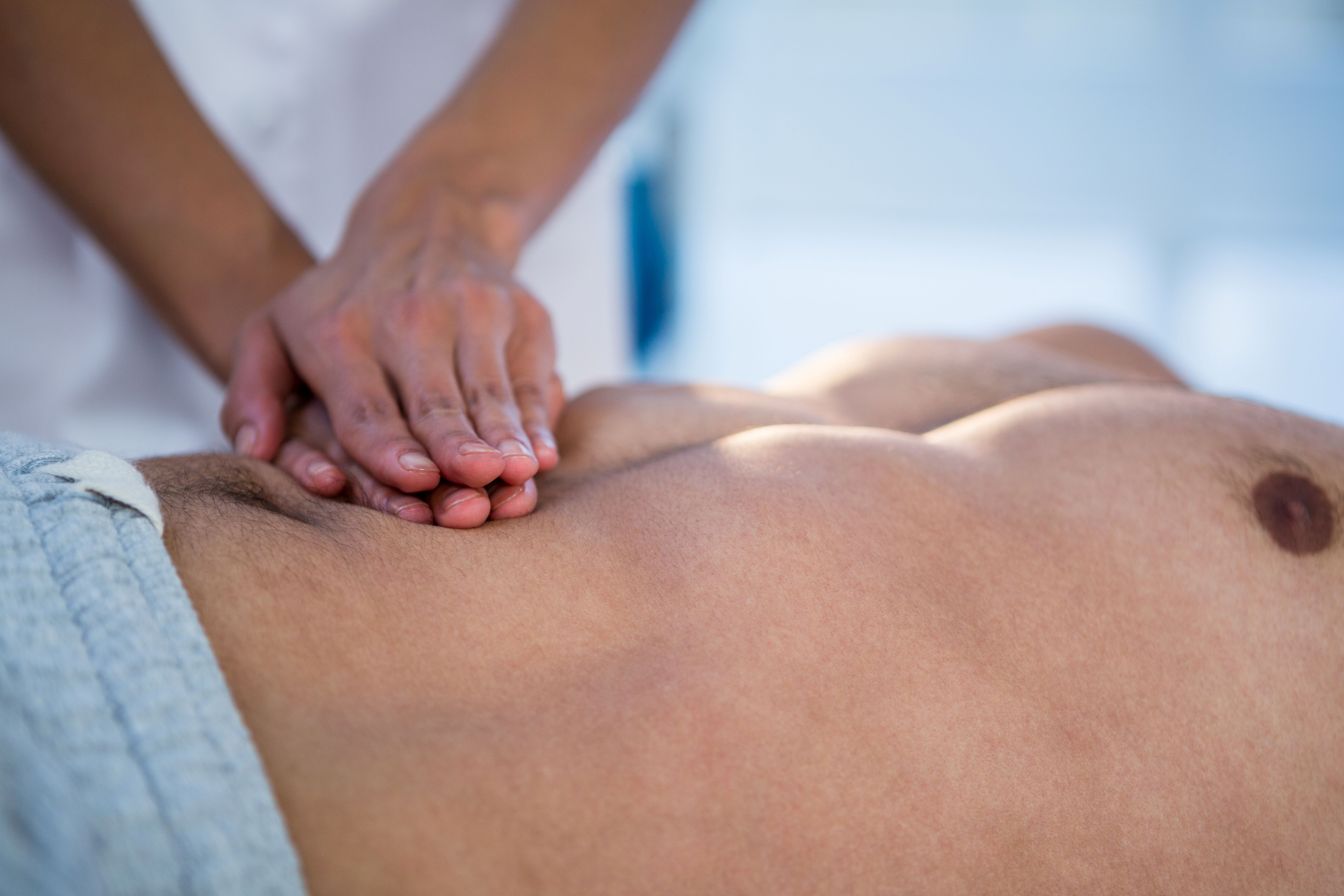 Physiotherapist giving stomach massage to a man