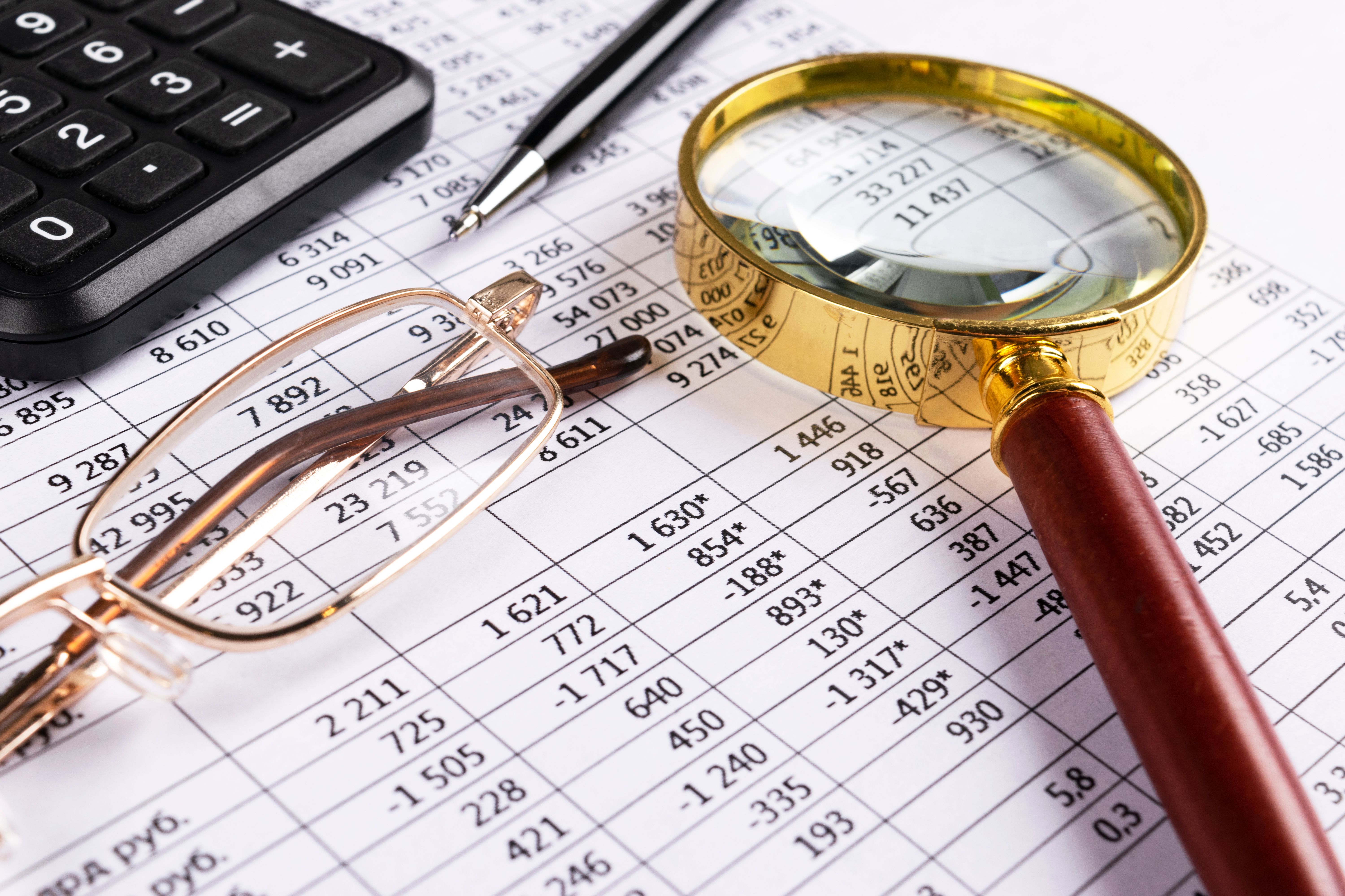 Financial concept. Calculator, pen and glasses on financial documents. Financial accounting. Balance sheets. Closeup of financial statements and annual reports. Business marketing