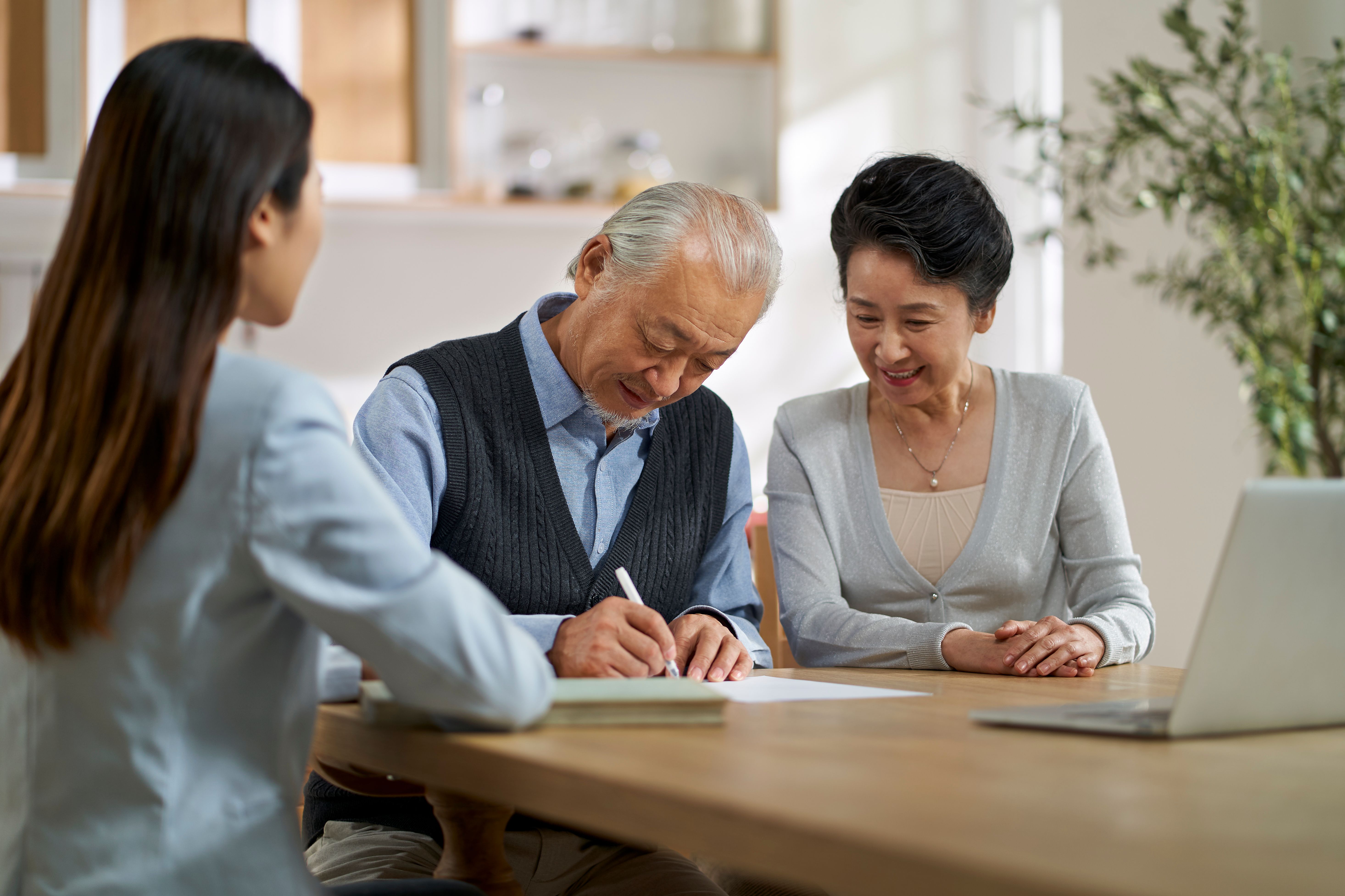 senior asian couple signing a contract at home