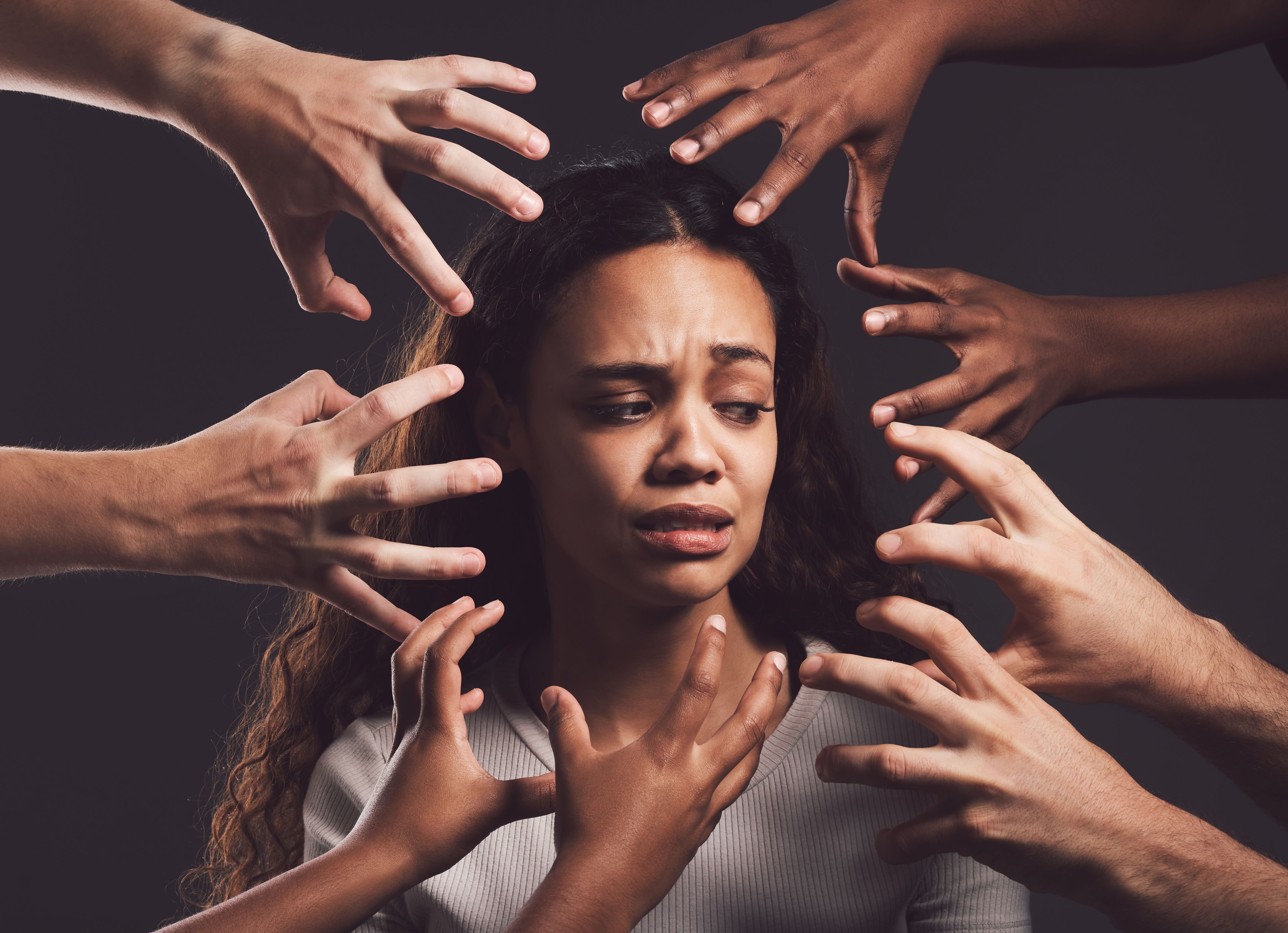 Shot of hands grabbing a young woman’s against a dark background