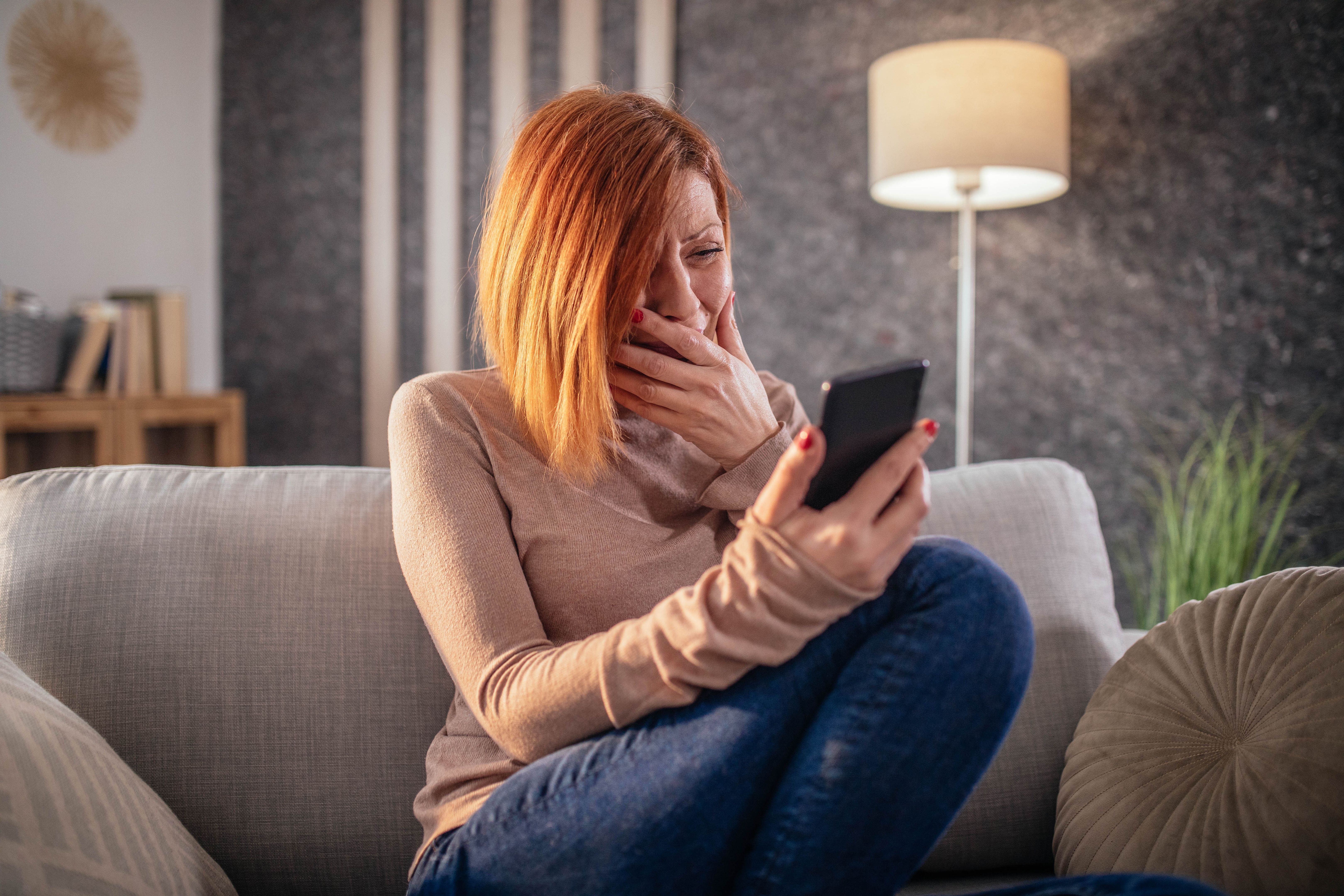 depressed woman at home using smartphone and laptop