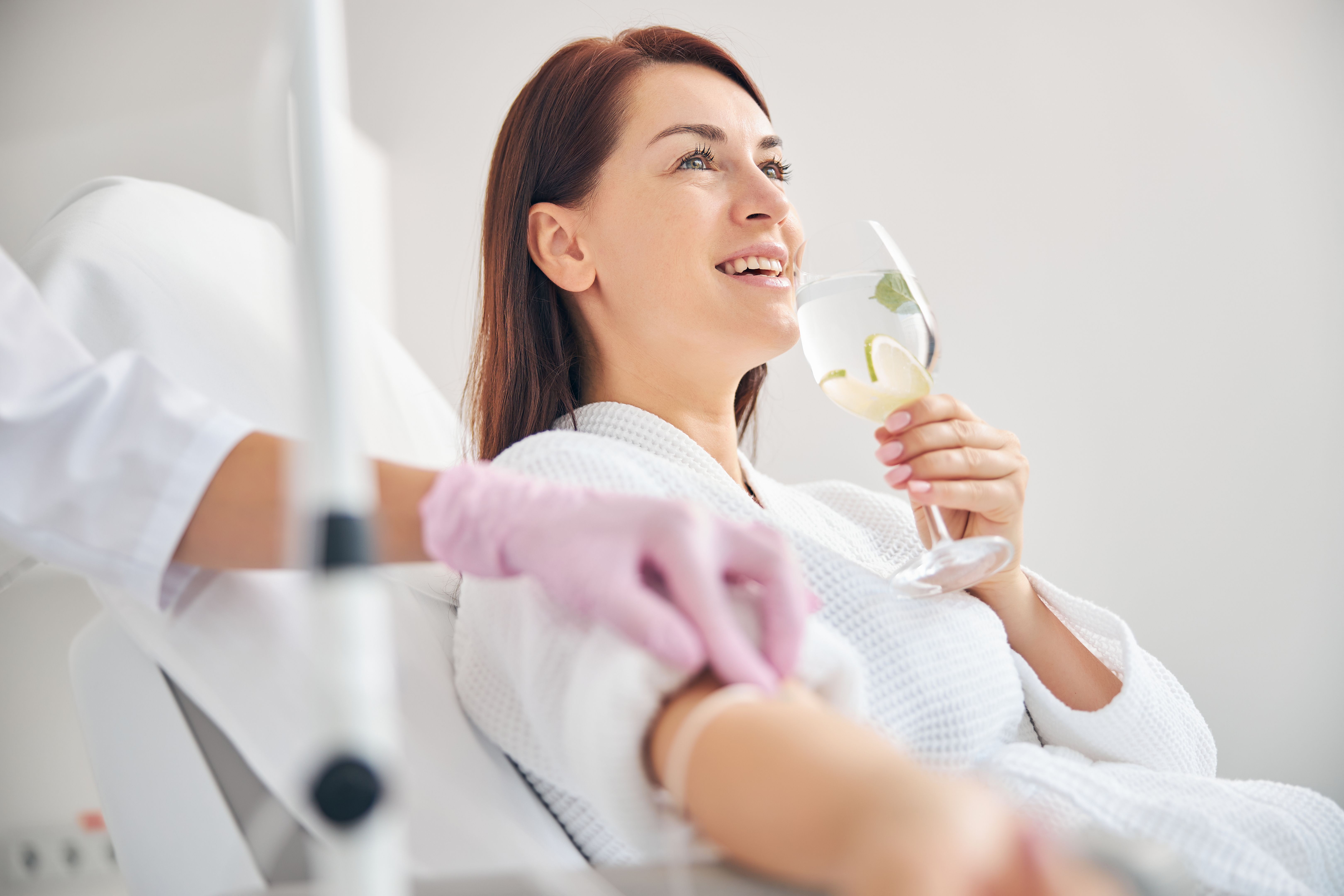 Attractive dark-haired woman smiling during the intravenous therapy Attractive dark-haired woman smiling during the intravenous therapy
