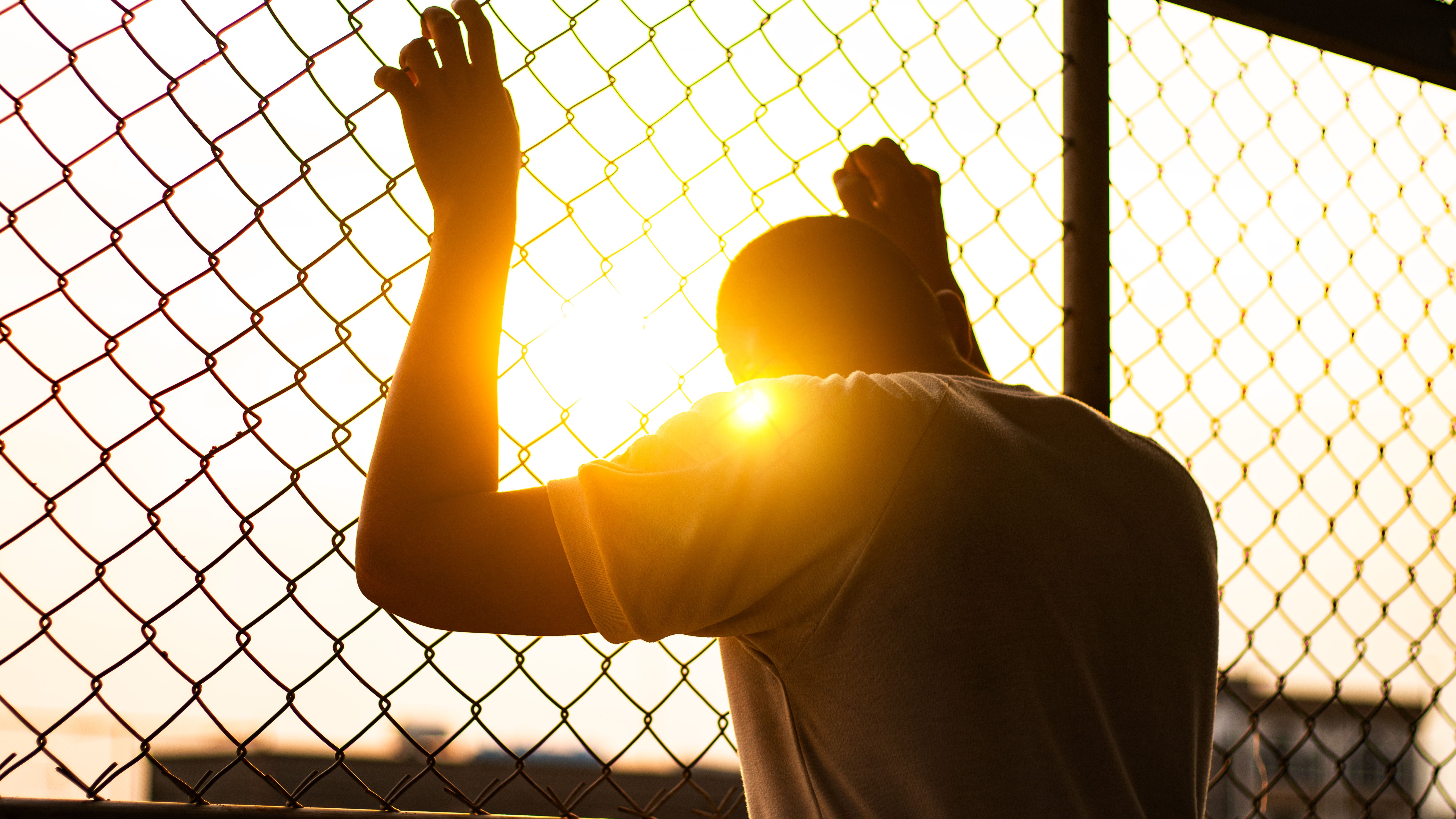 Silhouette of a man behind the fence, Silhouette photo of  feeling upset, sad, unhappy or disappoint crying. Young people mental health care problem lifestyle concept, frustrated standing hopelessly