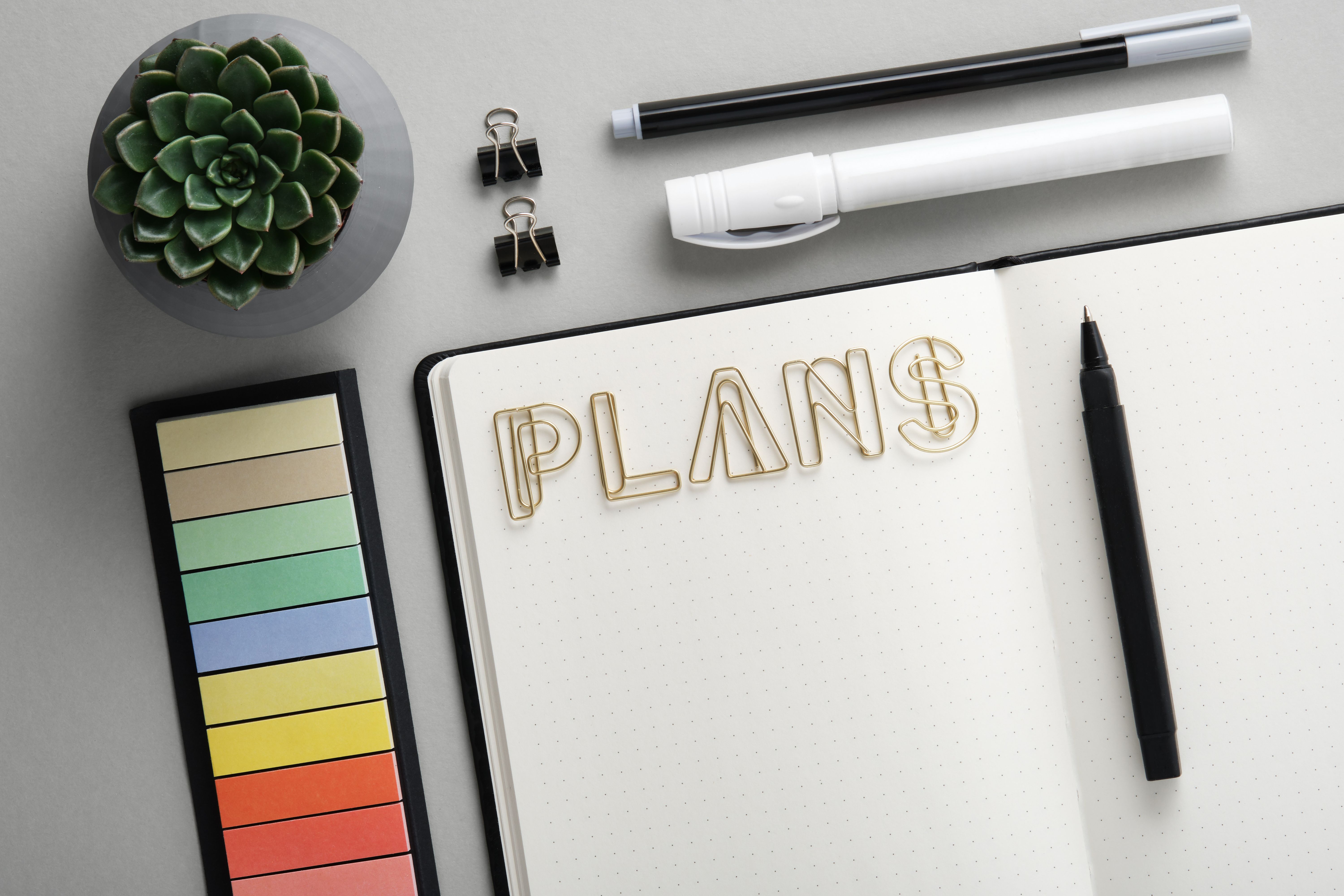 Open diary for plans with with black and white school and office stationery on gray background. Flatly. Concept of planning and resolution. Open diary for plans with with black and white school and office stationery on gray background. Flatly. Concept of planning and resolution.