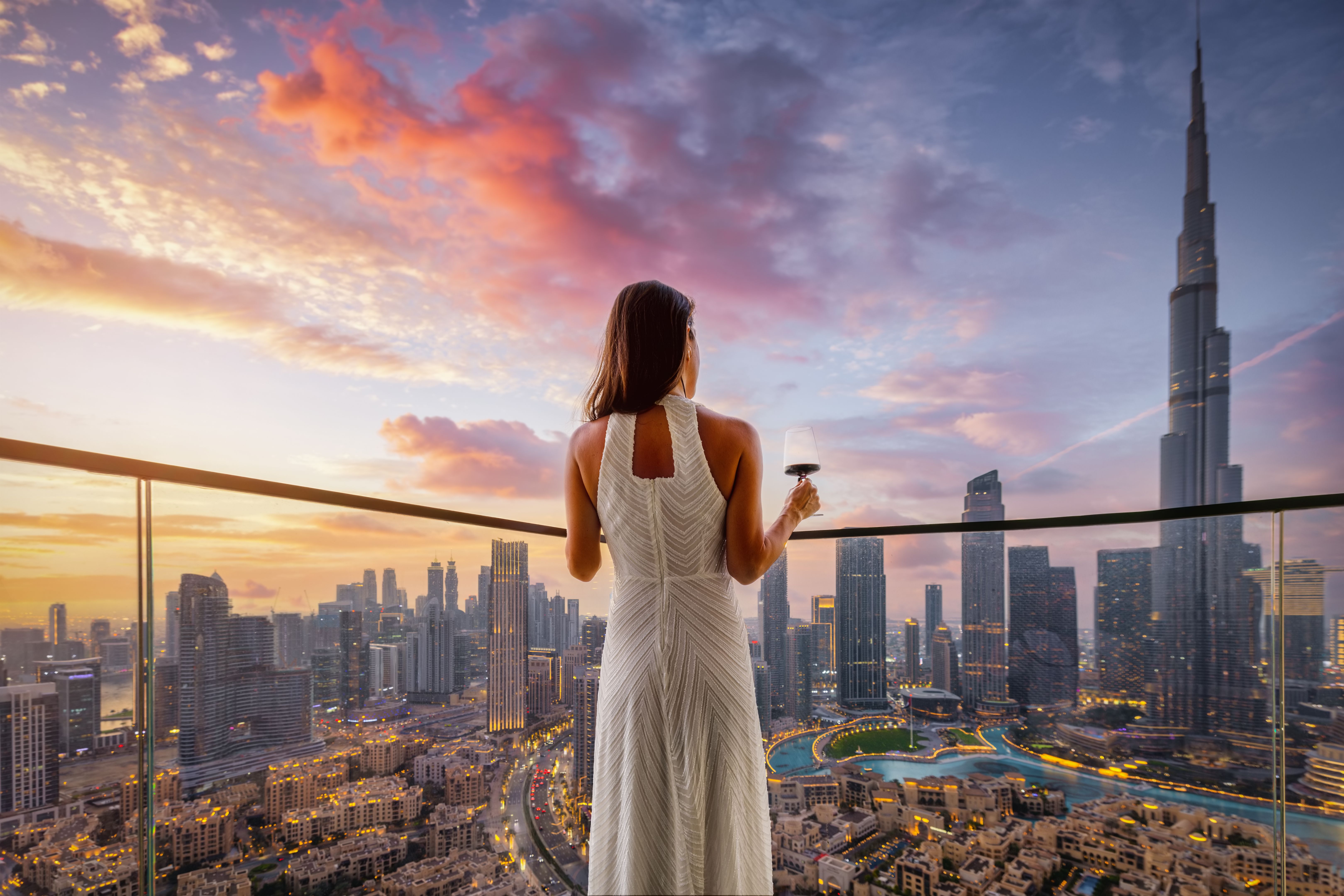 A woman enjoys the beautiful sunset view behind the skyline of Dubai