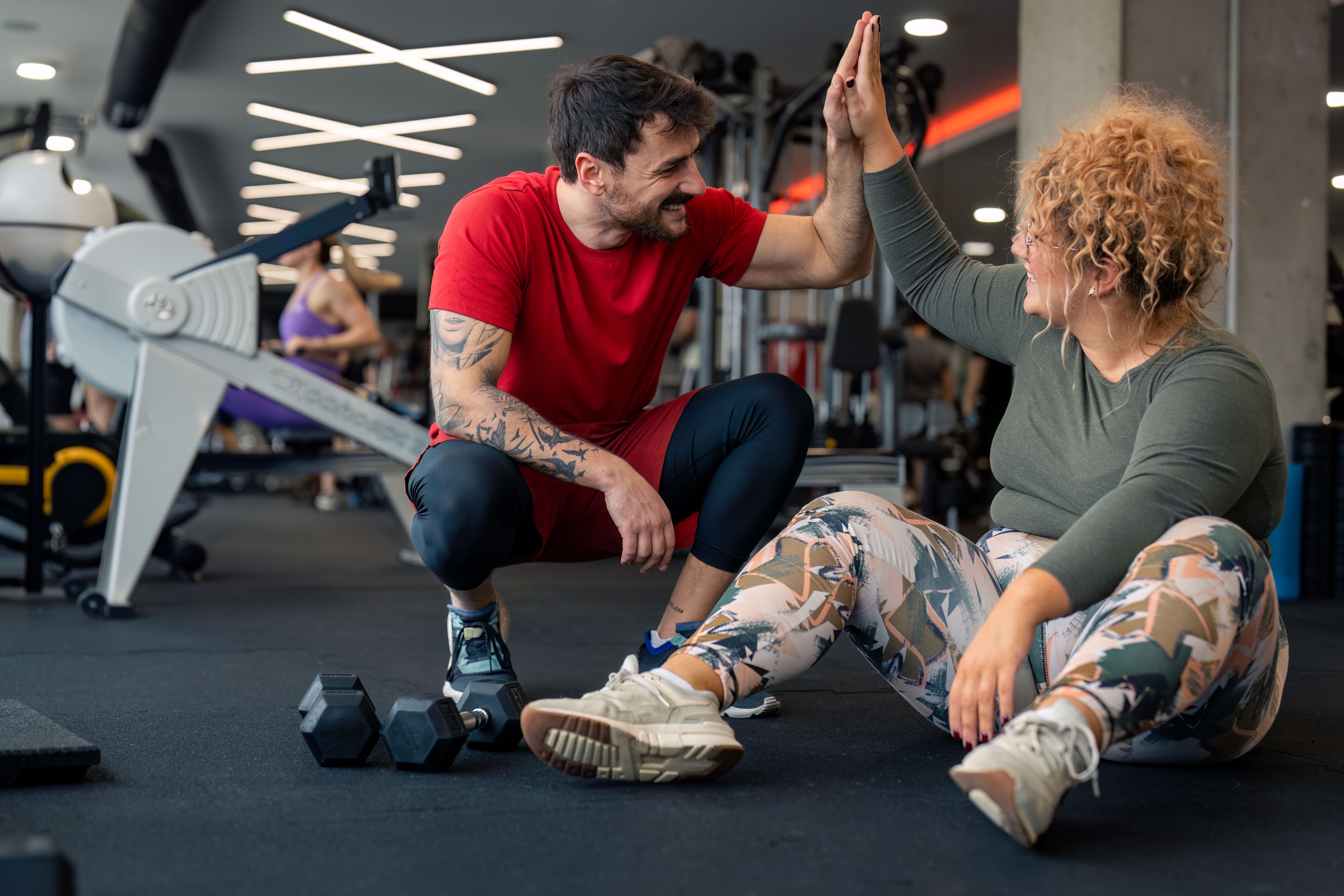 Supportive coach giving woman high-five after successful personal training session in gym Supportive coach giving woman high-five after successful personal training session in gym