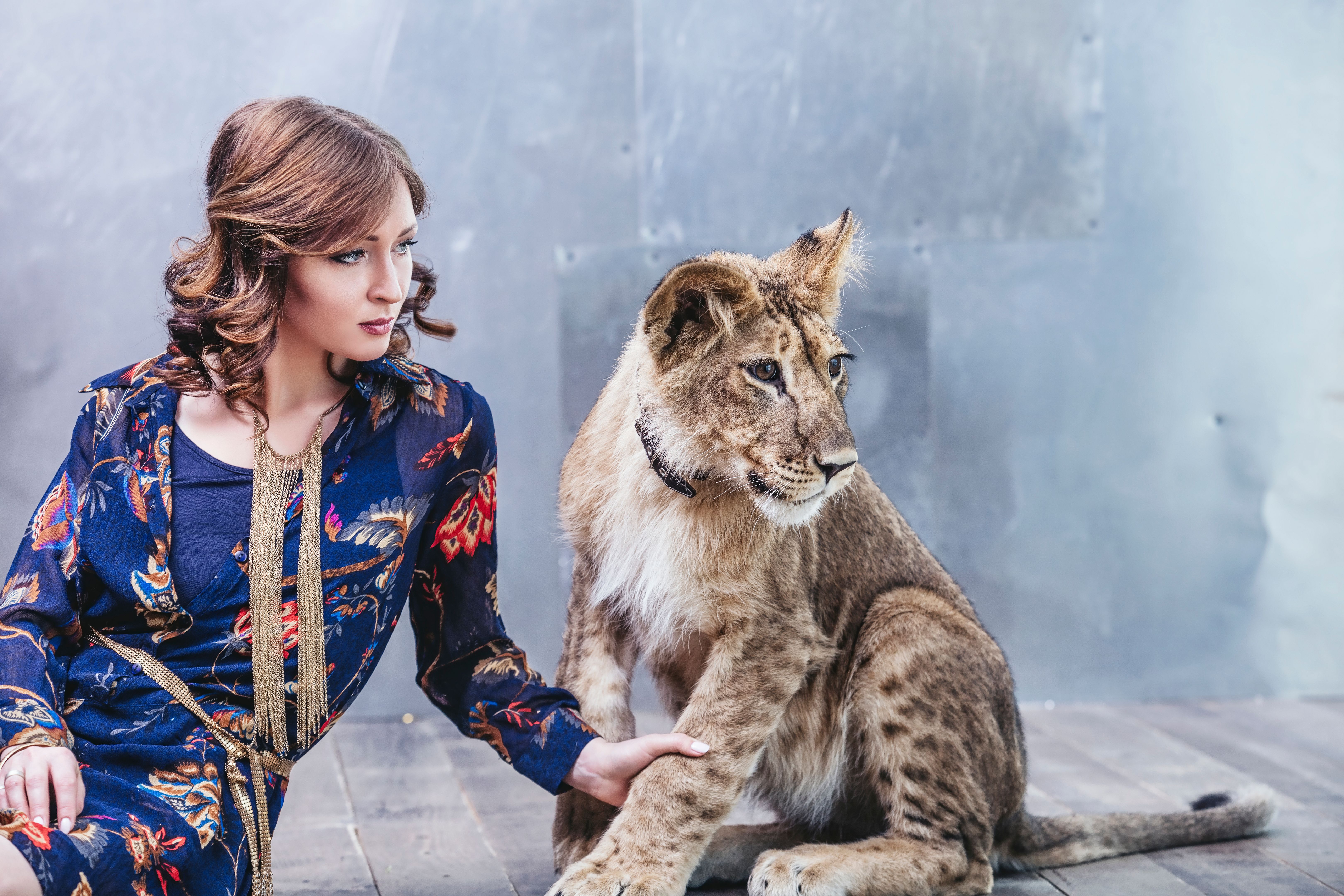 Beautiful fashionable young woman with a little alive lion cub Beautiful fashionable young woman with a little alive lion cub