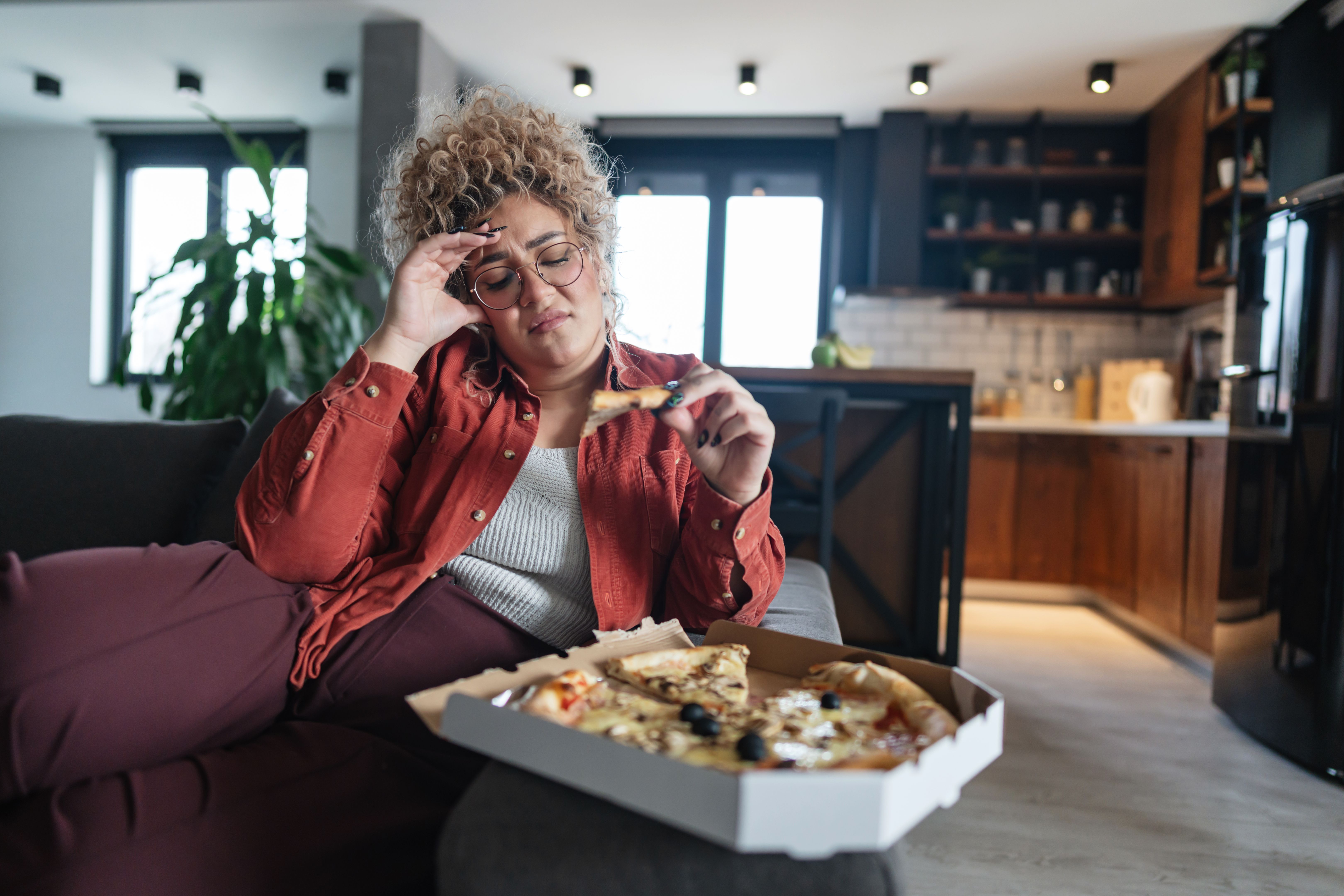 Young Woman Feeling Sick After Eating Pizza at Home Young Woman Feeling Sick After Eating Pizza at Home