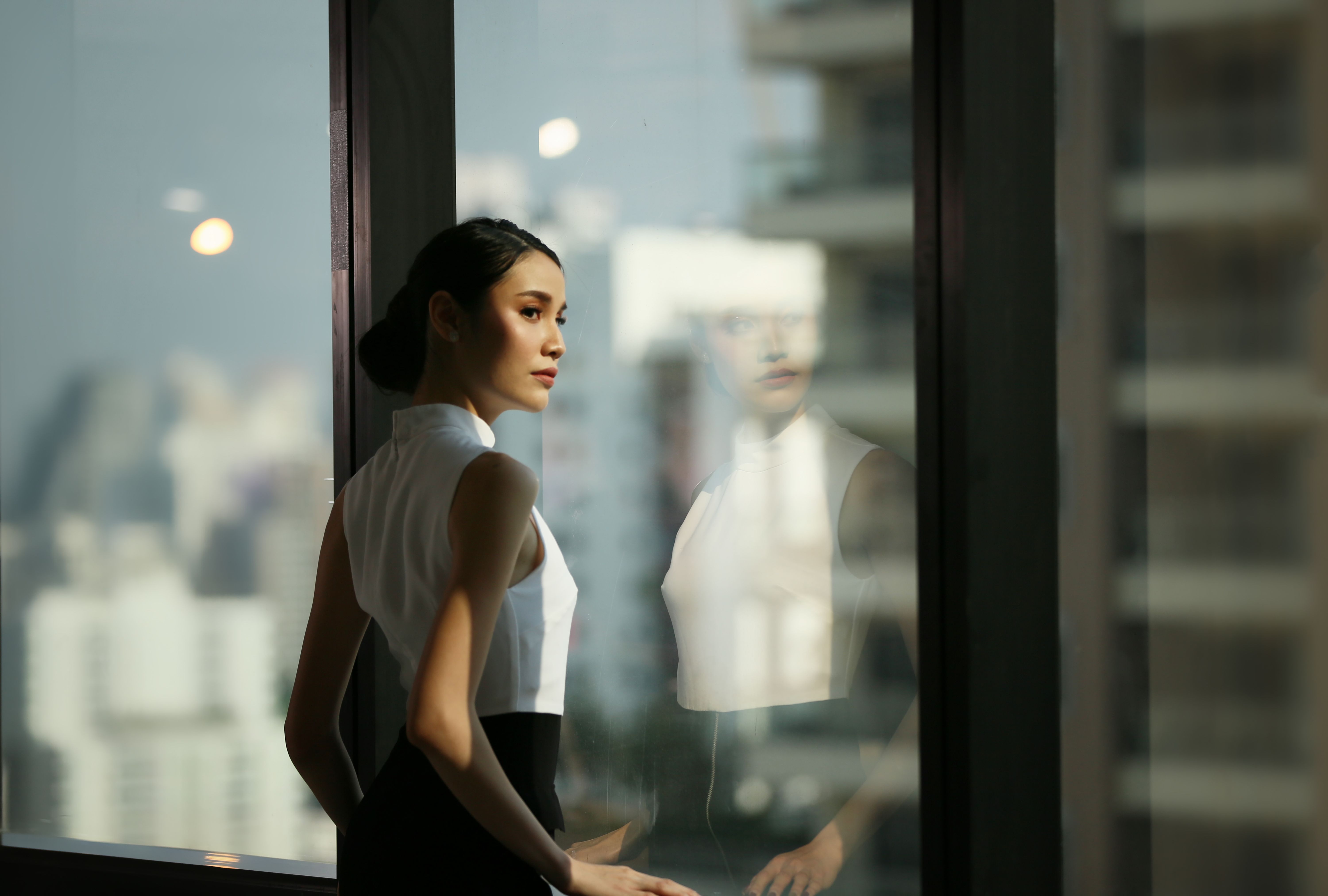 Businesswoman Looking Away While Standing By Window At Office