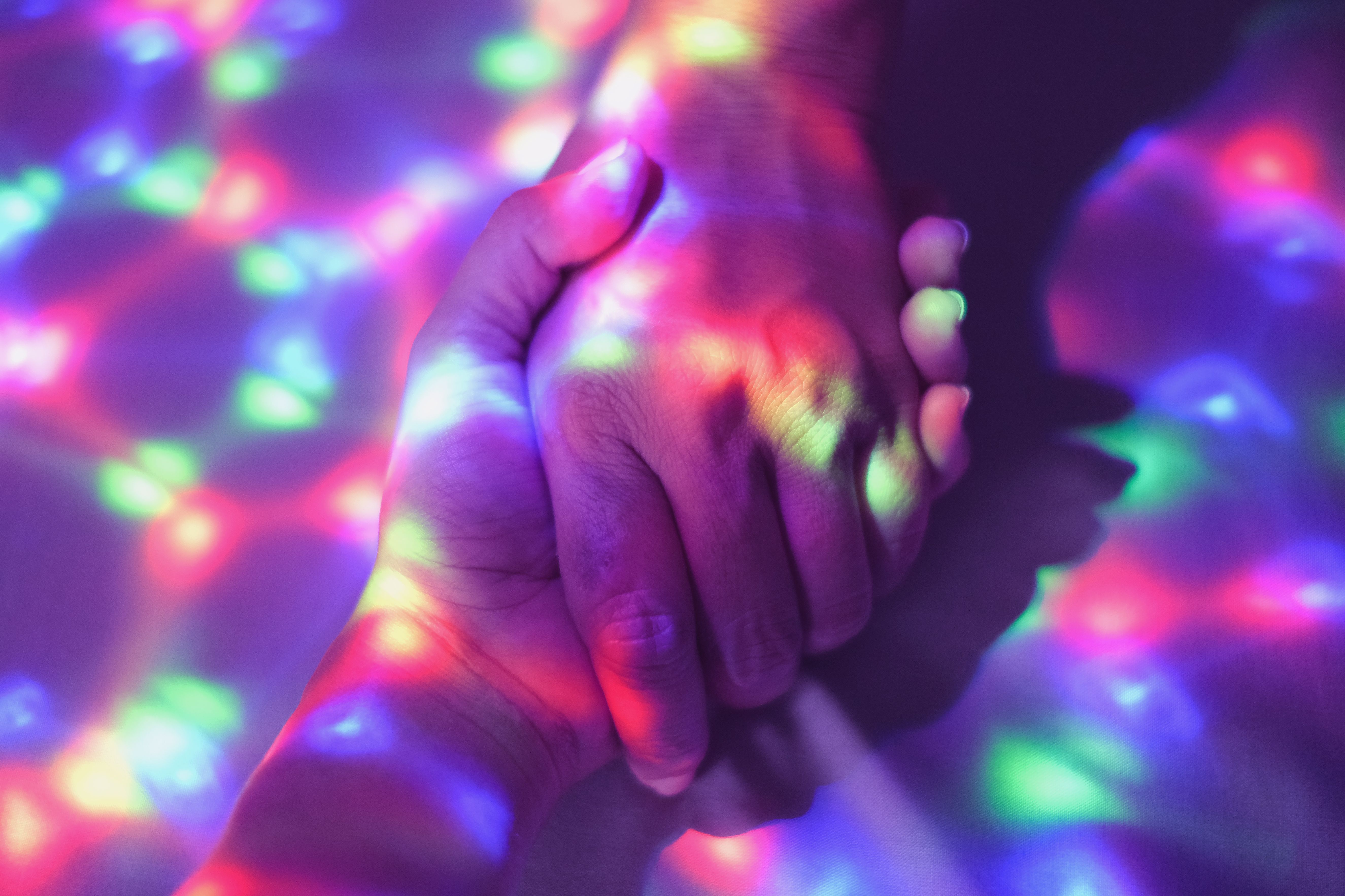 Close-Up of Hands Held Under Colorful Virtual Projection Lights