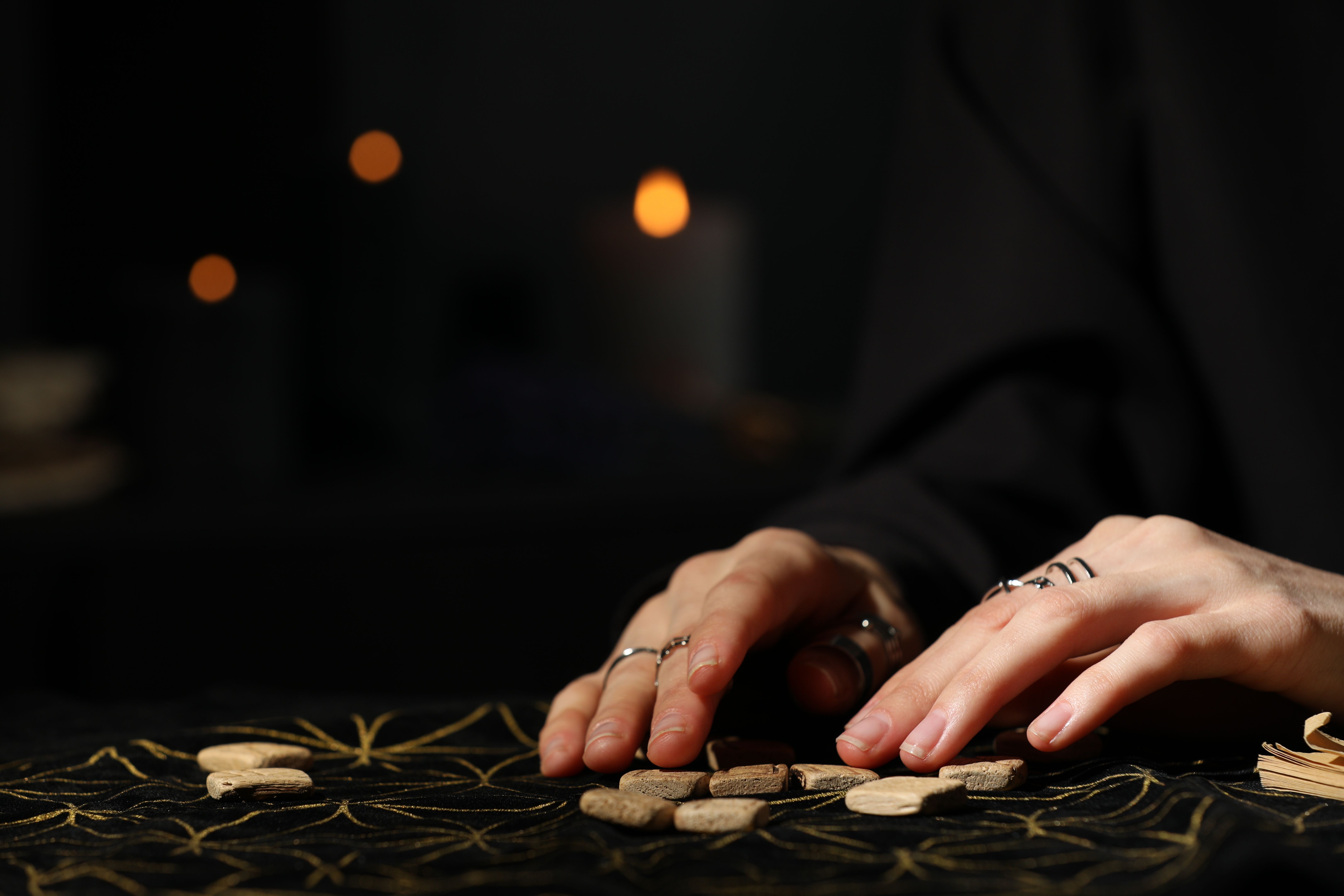 Woman with wooden runes at divination mat, closeup