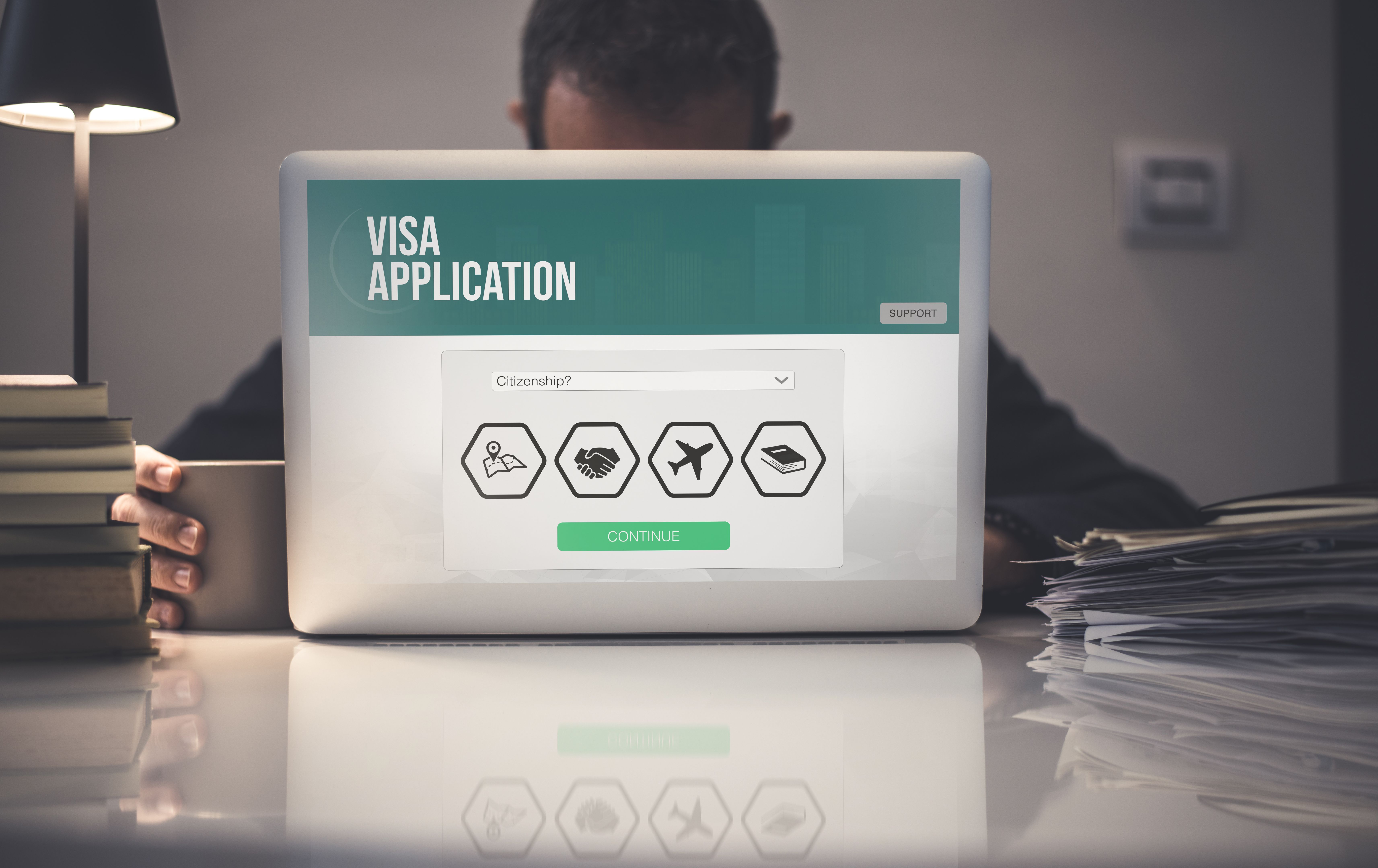 Hands filling visa application form on laptop. Work recruitment, study, travel, immigration concept.