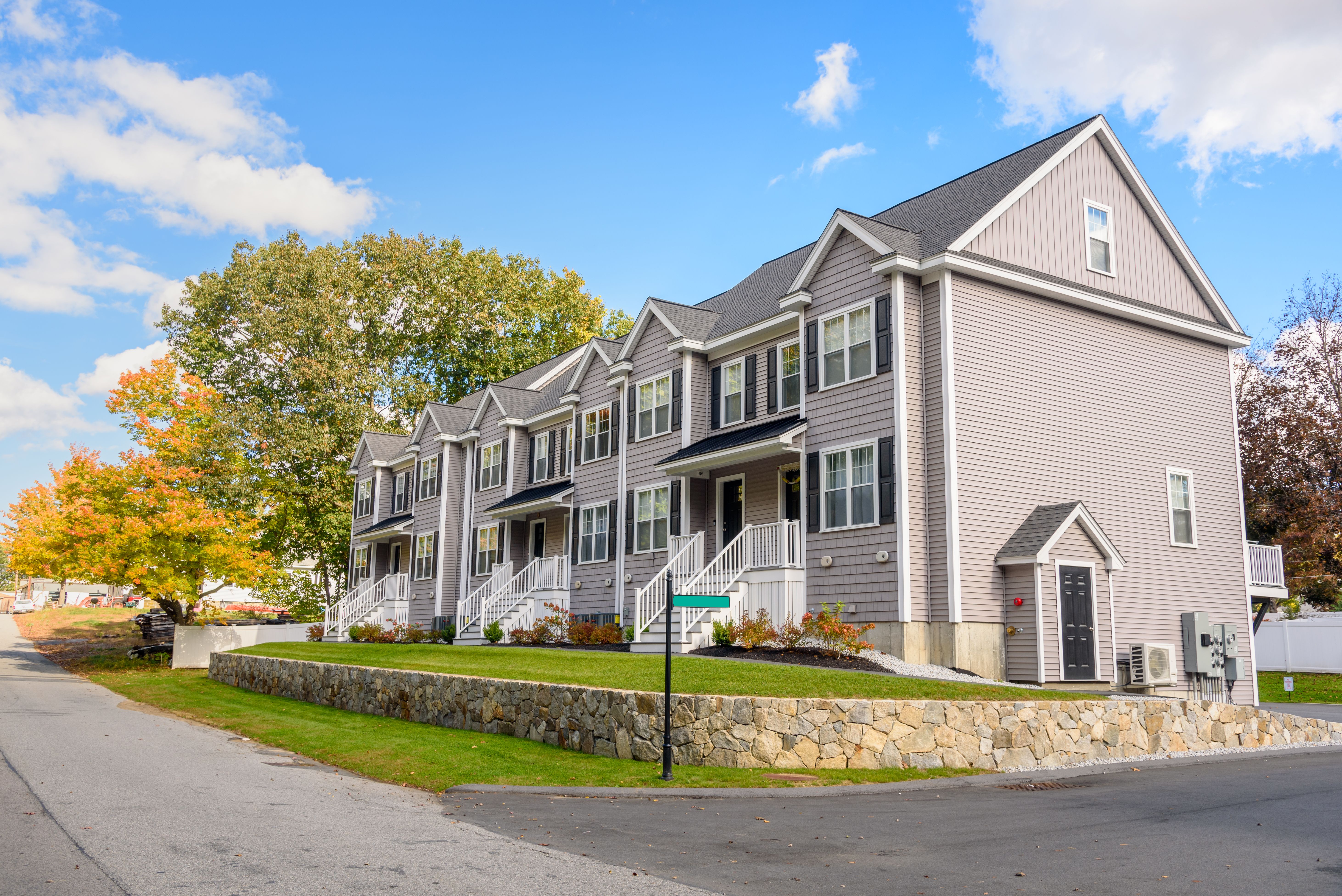 New Row houses with white stairs leading to the front doors on a sunny autumn day