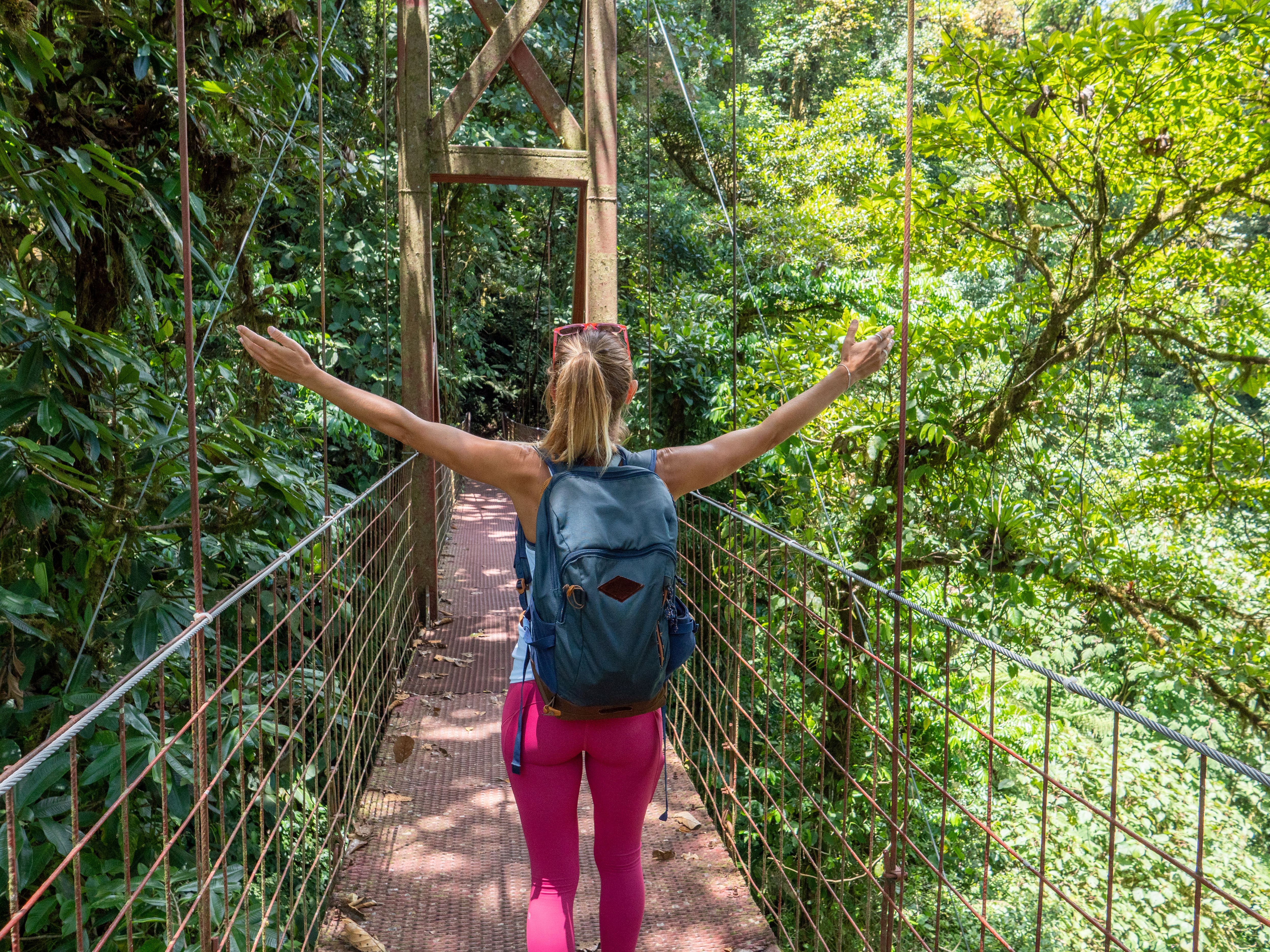 Young woman wandering in tropical rainforest in Costa Rica, arms outstretched