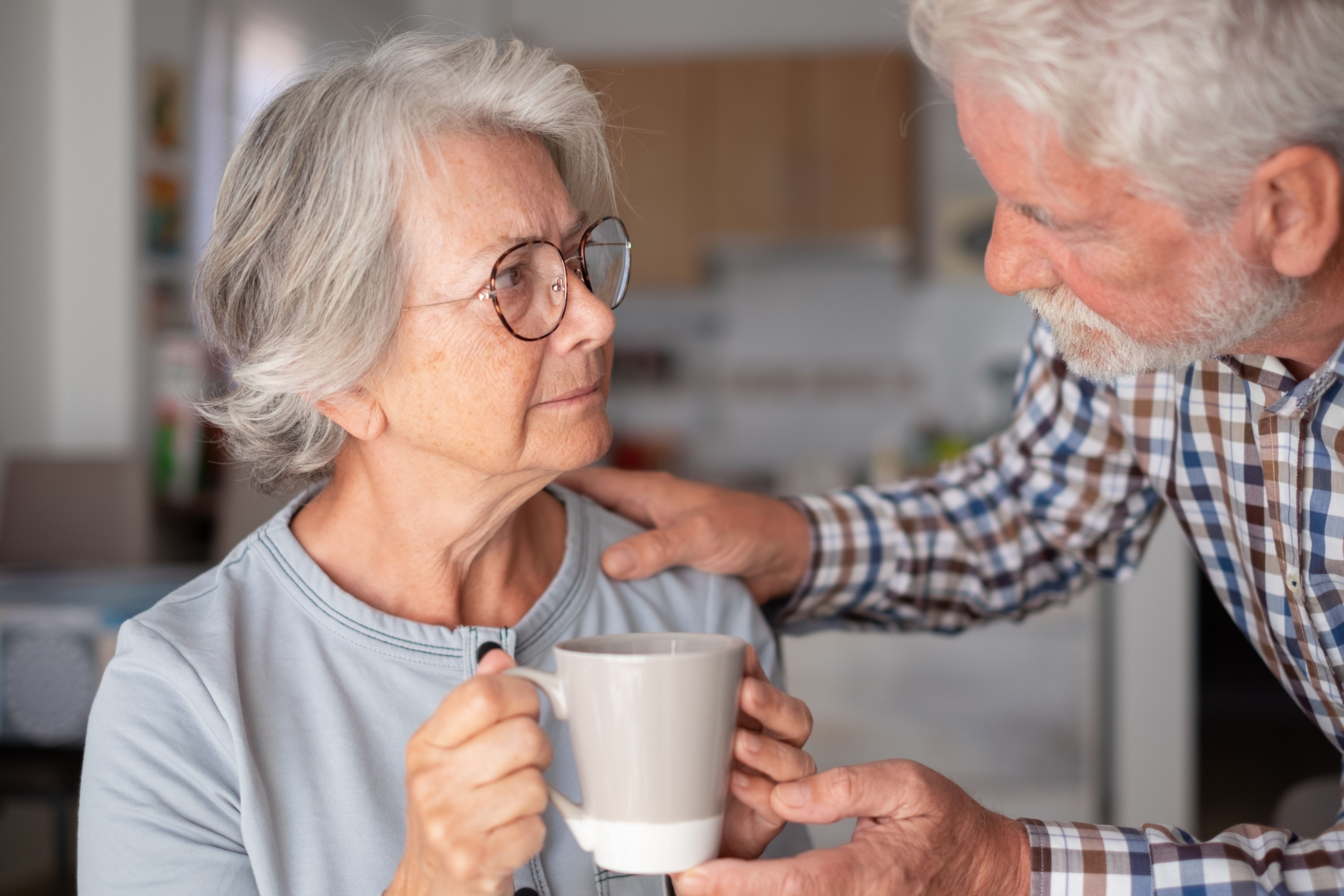 Sad and depressed elderly woman sitting at home while her husband tries to comfort her. Unhappy senior woman needs medical help. Our mind matters Sad and depressed elderly woman sitting at home while her husband tries to comfort her. Unhappy senior woman needs medical help. Our mind matters