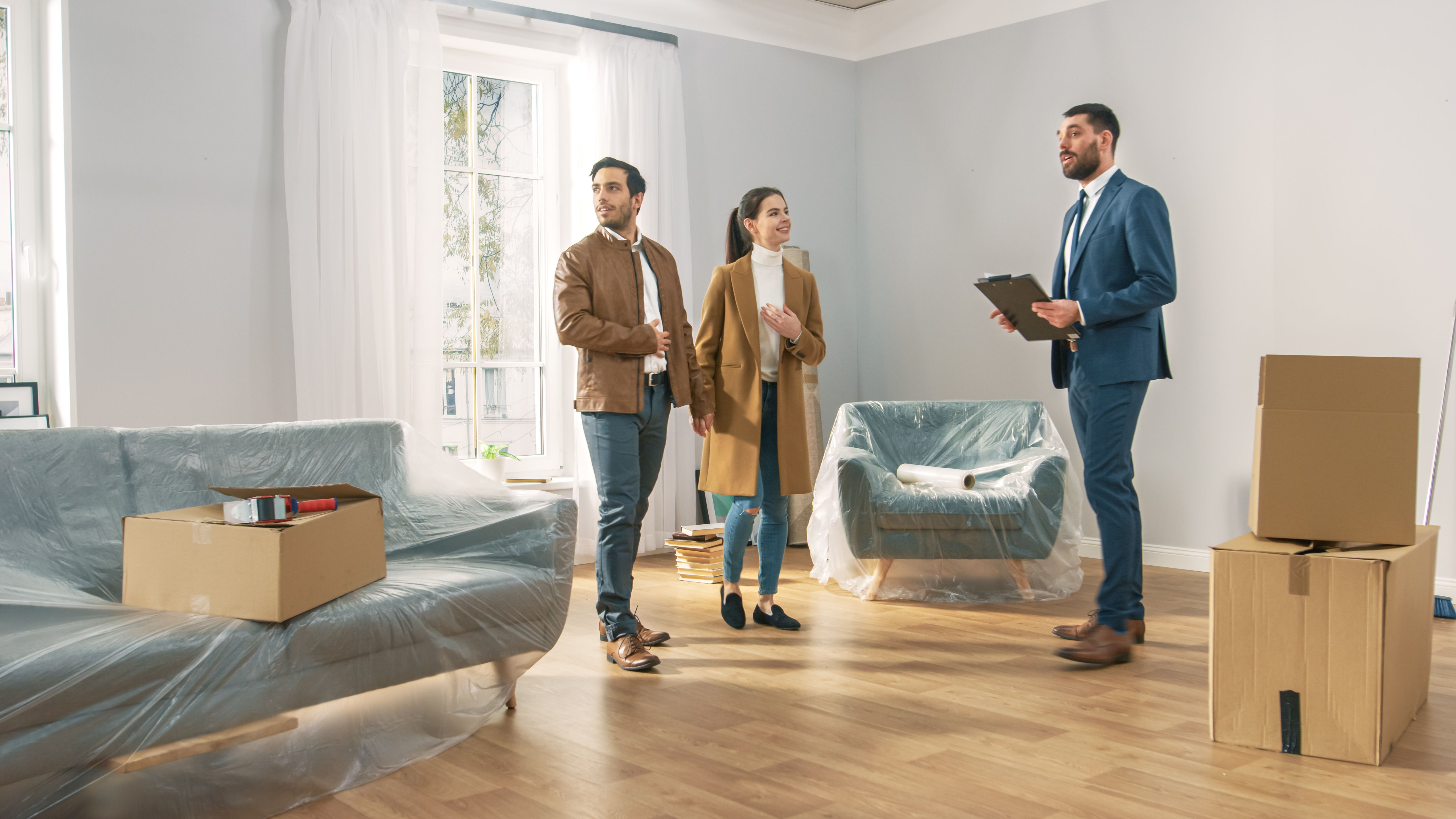 Professional Real Estate Agent Shows Bright New Apartment to a Young Couple. Successful Young Couple Ready to Become Homeowners. Spacious Bright Home with Big Windows. Professional Real Estate Agent Shows Bright New Apartment to a Young Couple. Successful Young Couple Ready to Become Homeowners. Spacious Bright Home with Big Windows.