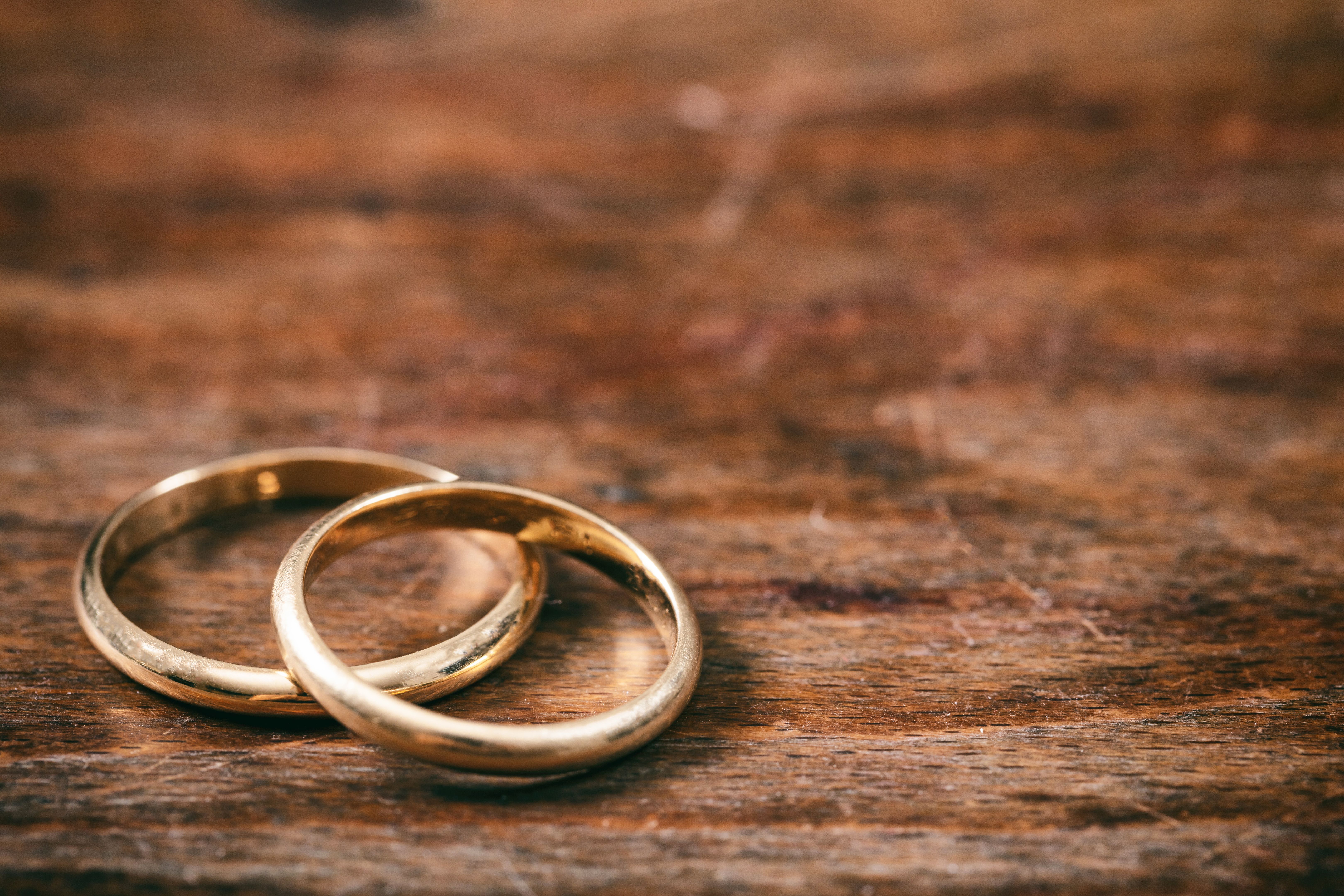 Two golden wedding rings on wooden background, copy space