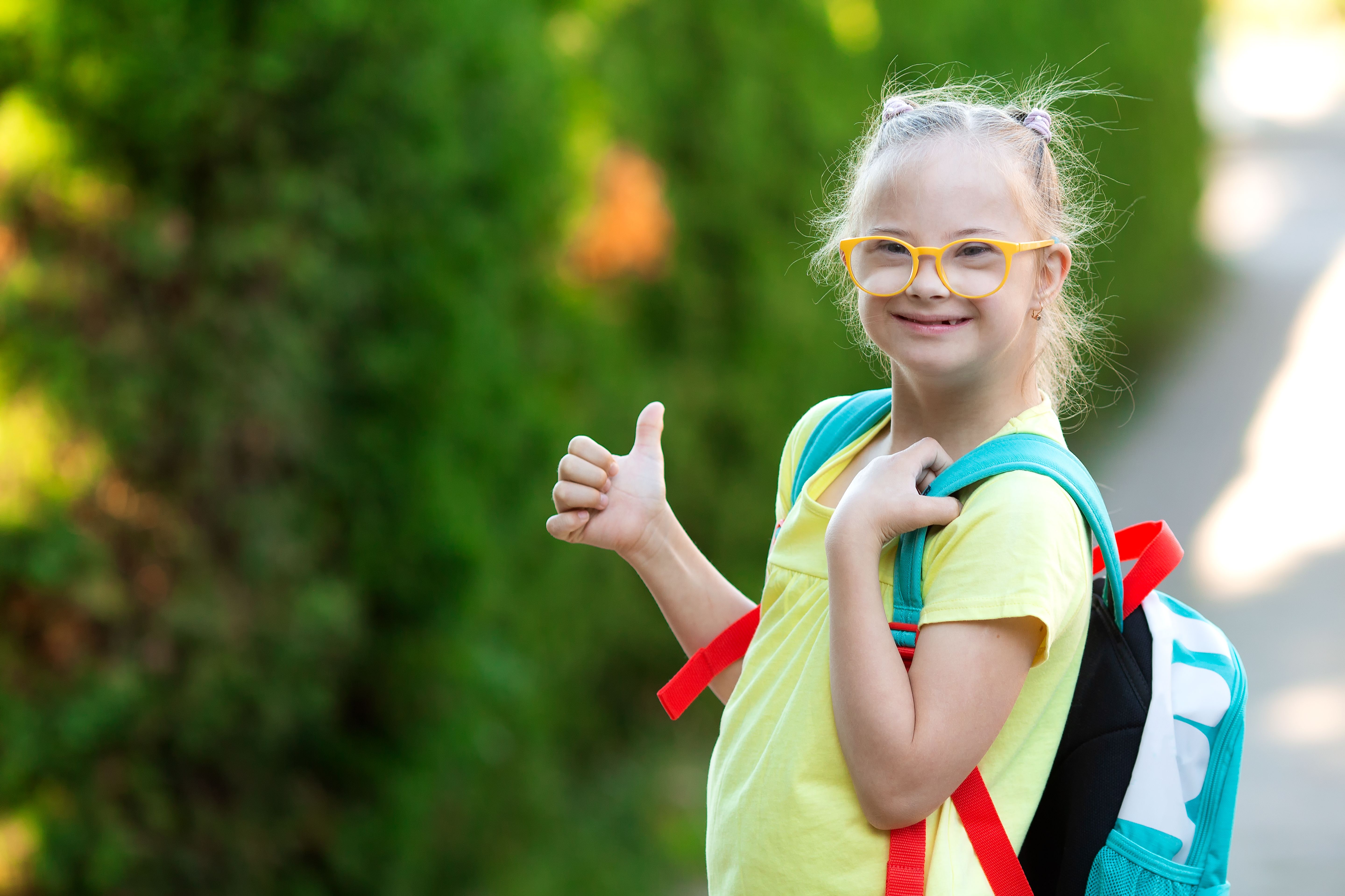 Une fille atteinte du syndrome de Down va à l’école avec un sac à dos
