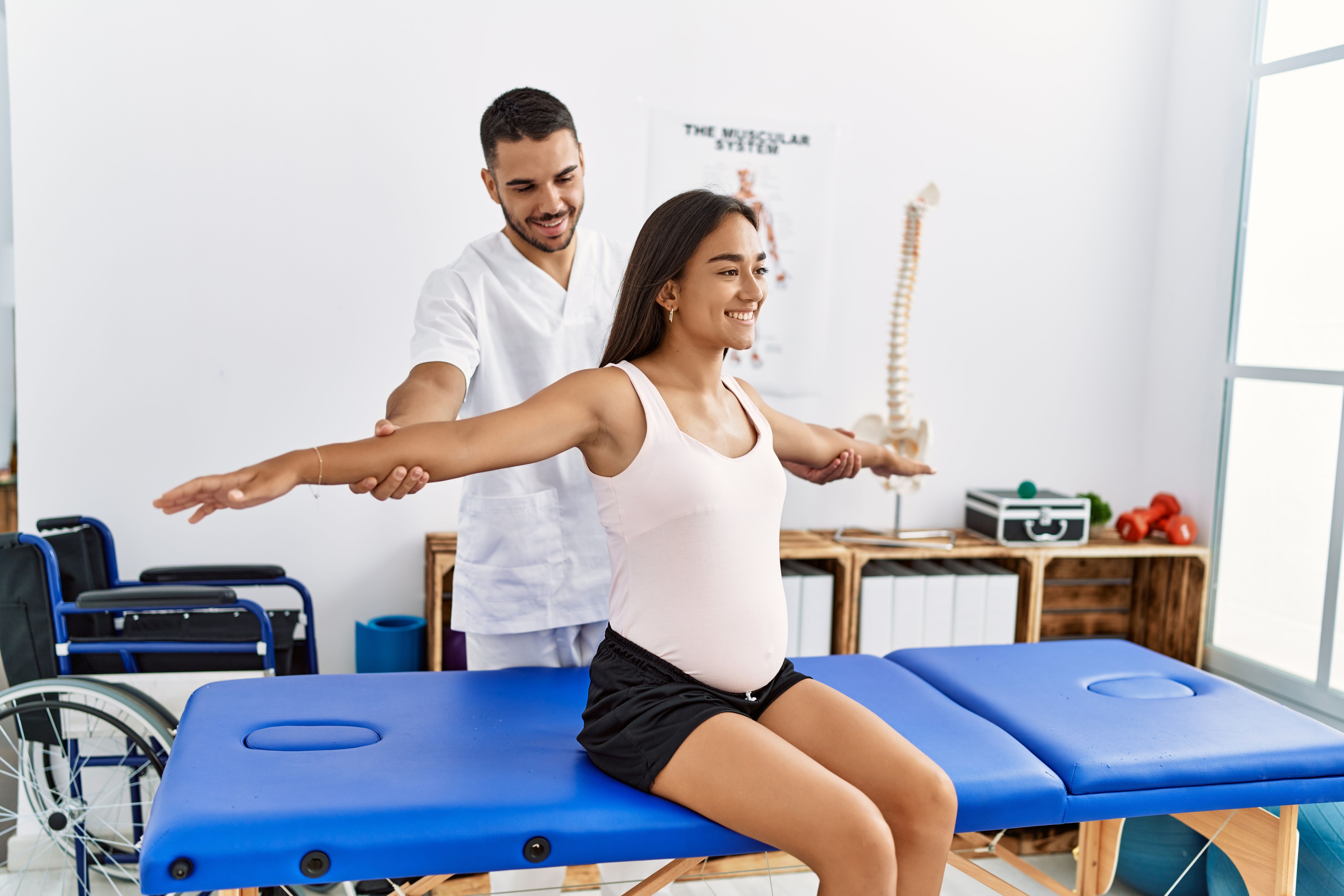 Latin man and woman wearing physiotherapist uniform having pregnancy rehab session at physiotherapy clinic Latin man and woman wearing physiotherapist uniform having pregnancy rehab session at physiotherapy clinic